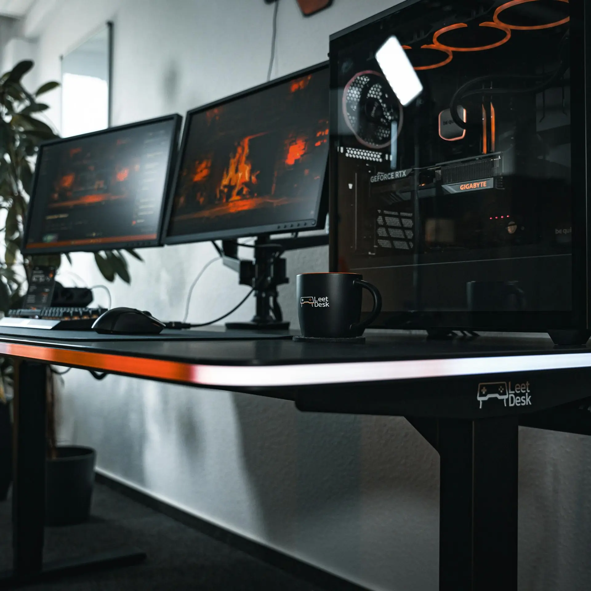 Ein Schreibtisch mit zwei Monitoren, einem PC und einer Tasse.
