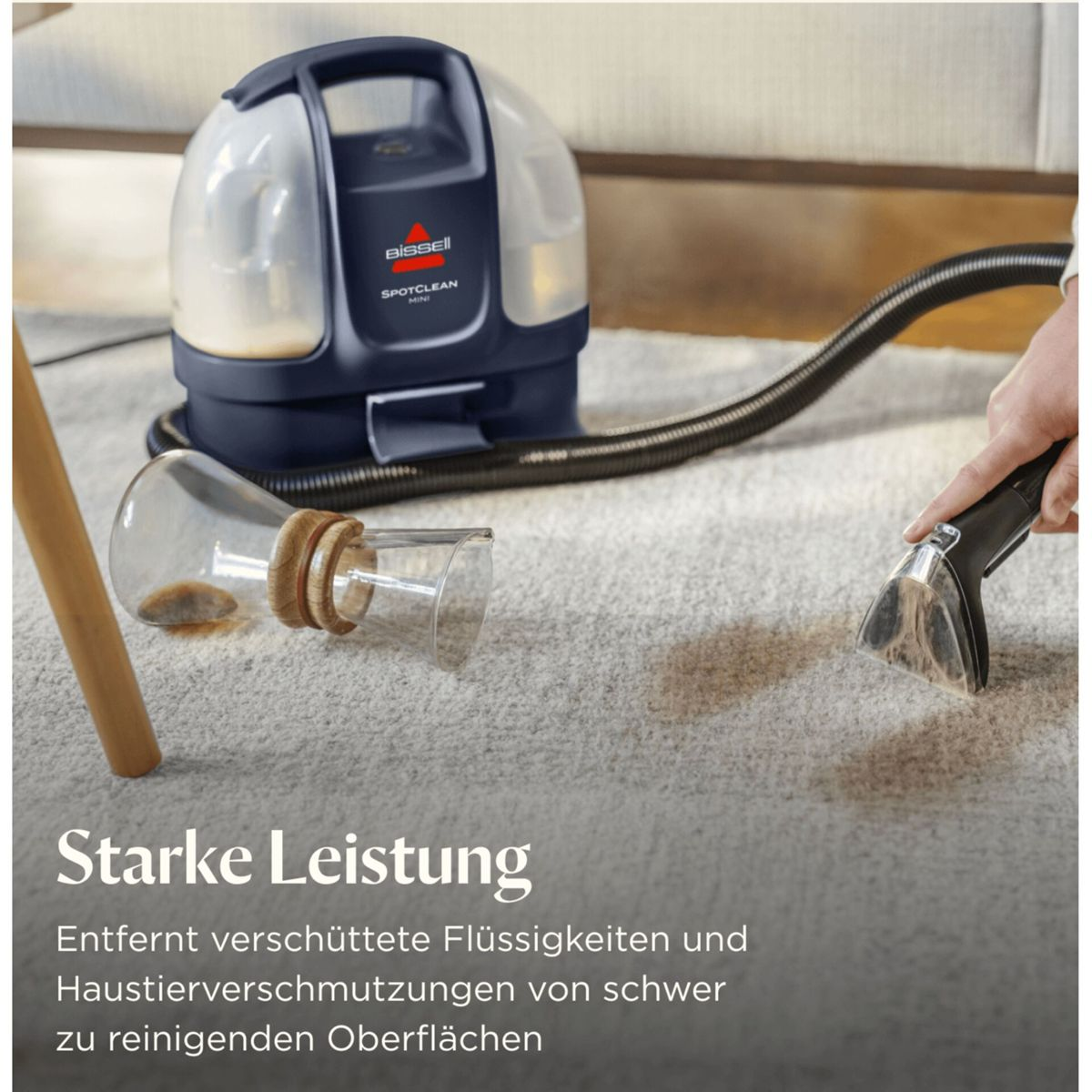 Ein Bissel SpotClean Mini reinigt Teppichflecken mit einem Schlauchaufsatz.