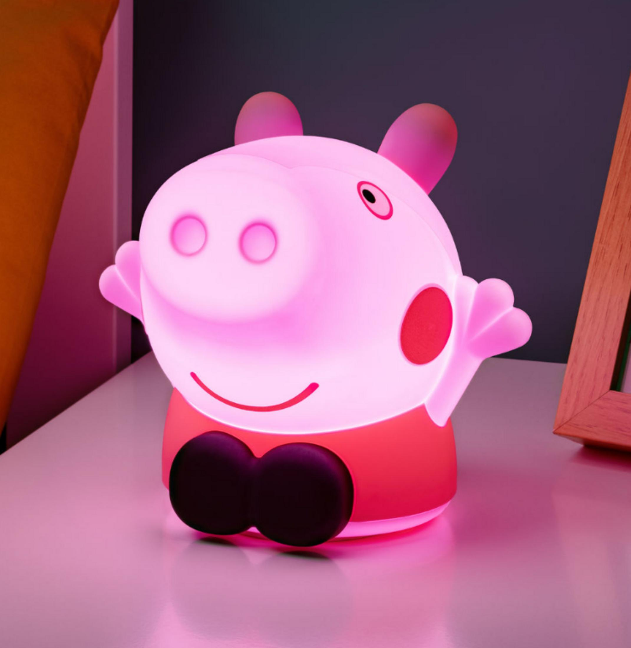 Różowa lampka Peppa z czarnymi stopami stoi na stole.