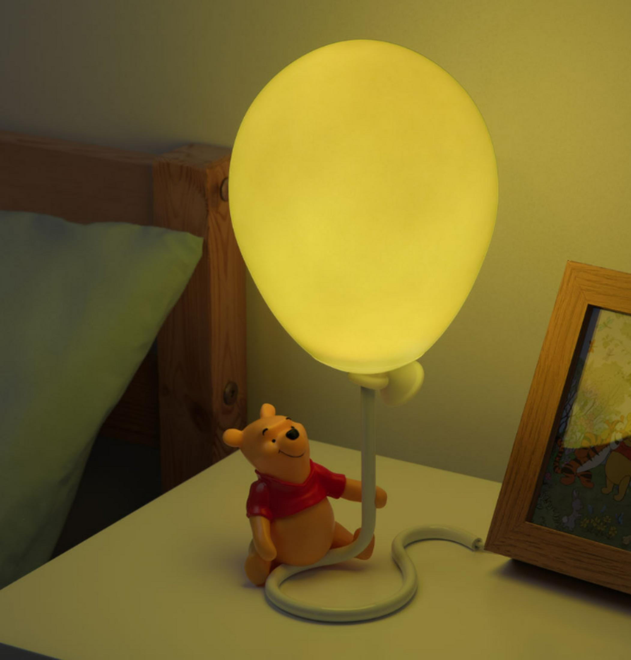 Winnie Puuh-Lampe in Ballonform auf Nachttisch mit Bilderrahmen.