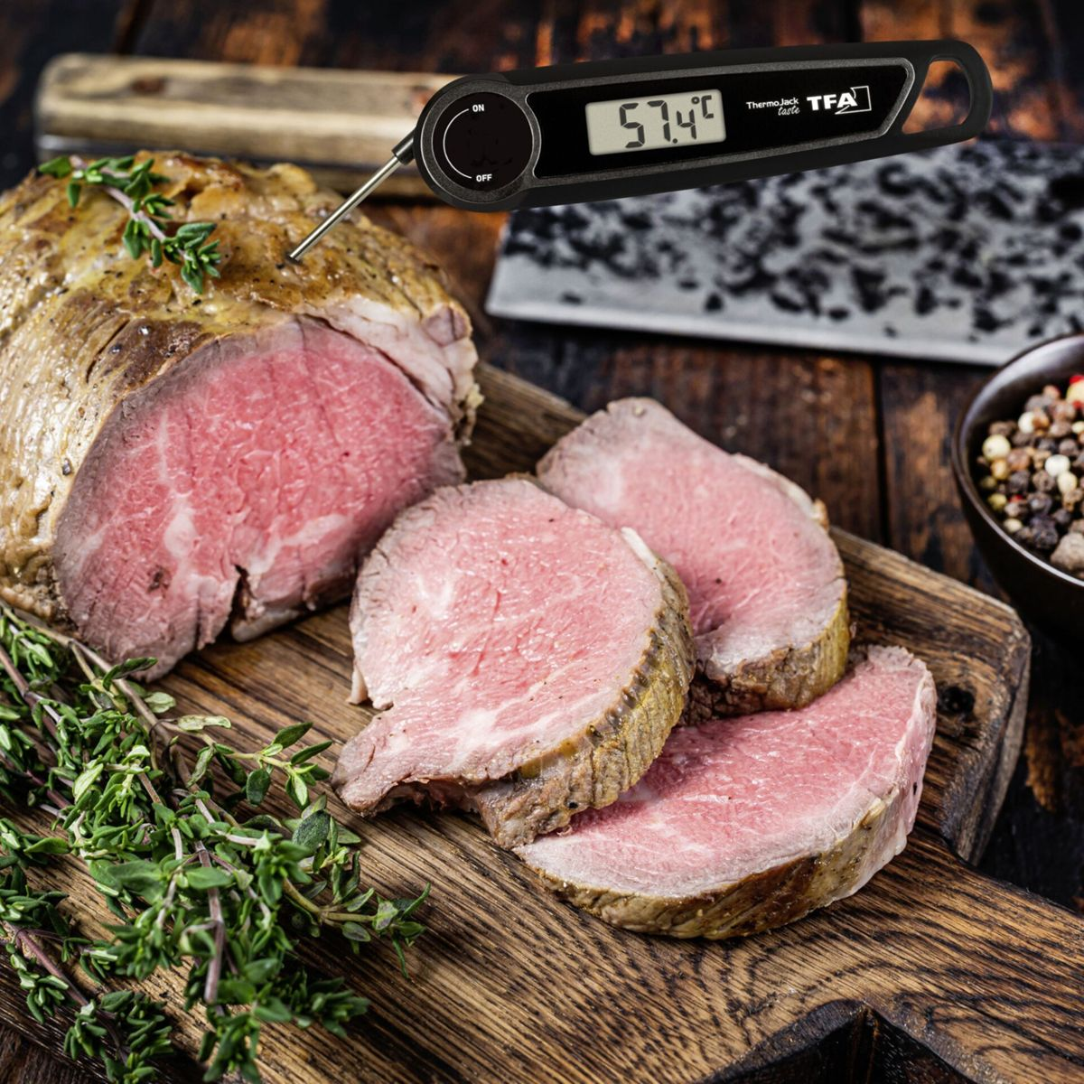 Ein digitales Fleischthermometer zeigt 57,4°C an, das auf einem saftigen Braten steckt.