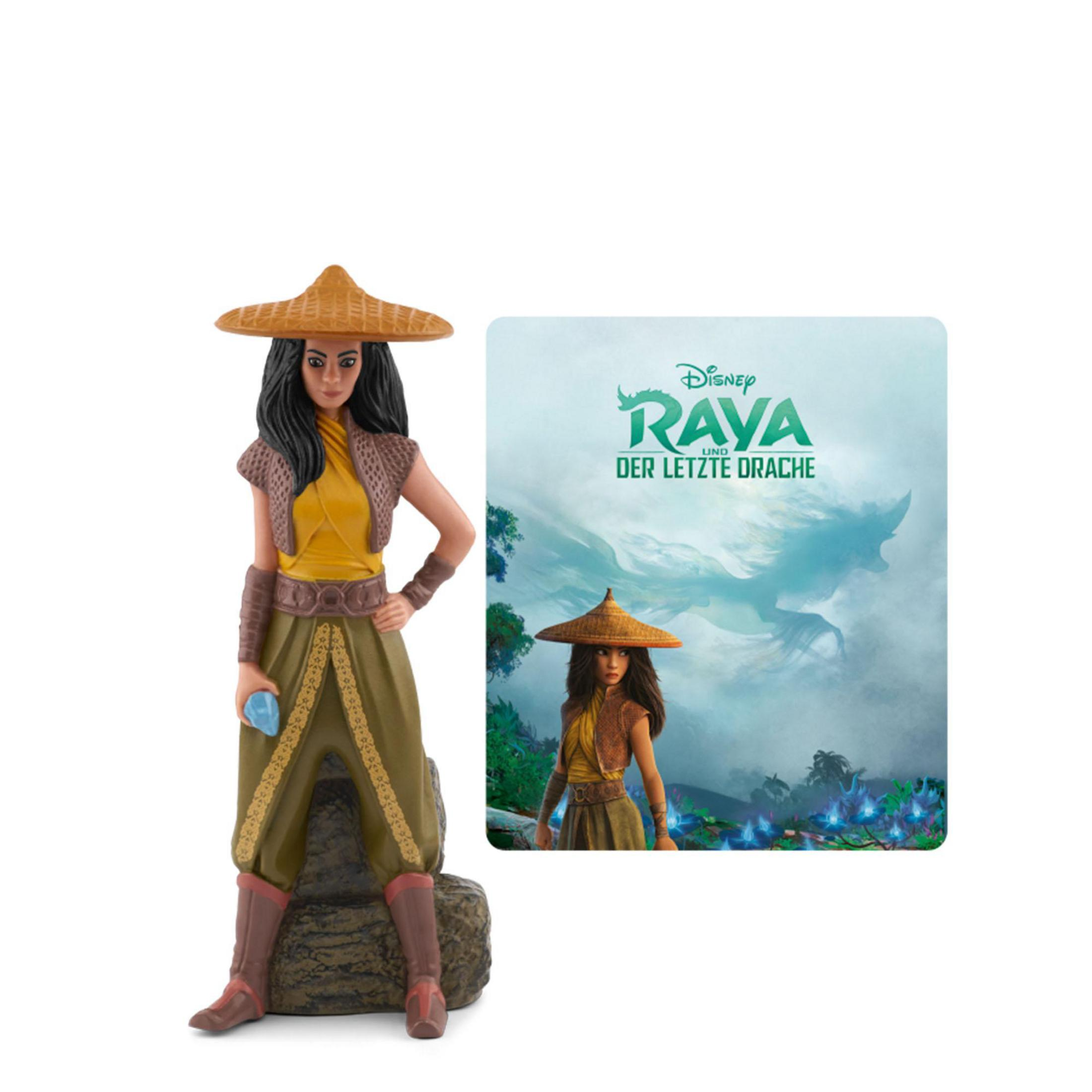 Raya-Figur mit breitkrempigem Hut, gelbem Oberteil und grünem Rock, hält blauen Stein.