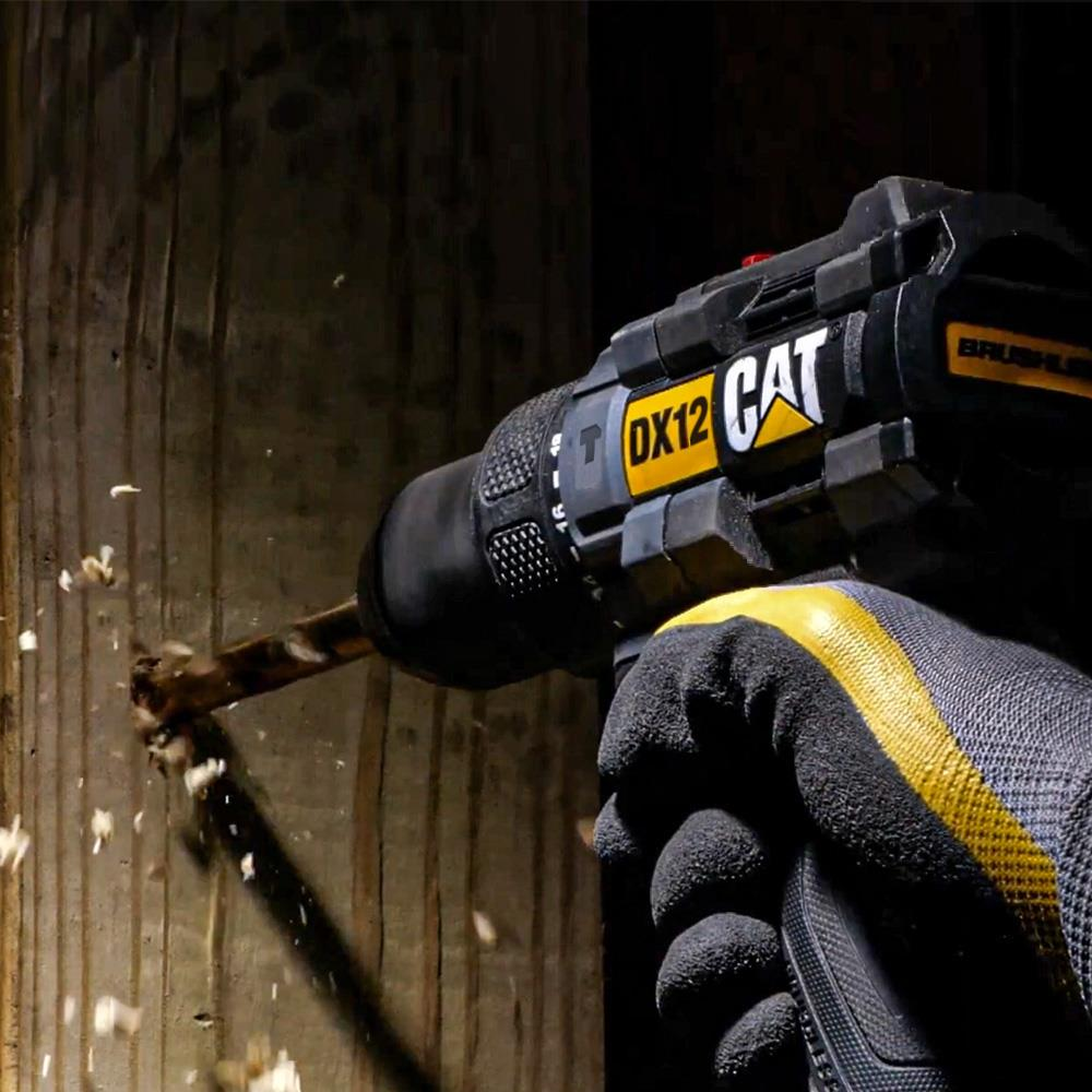 Un trapano con logo giallo CAT fora legno. Volano trucioli.