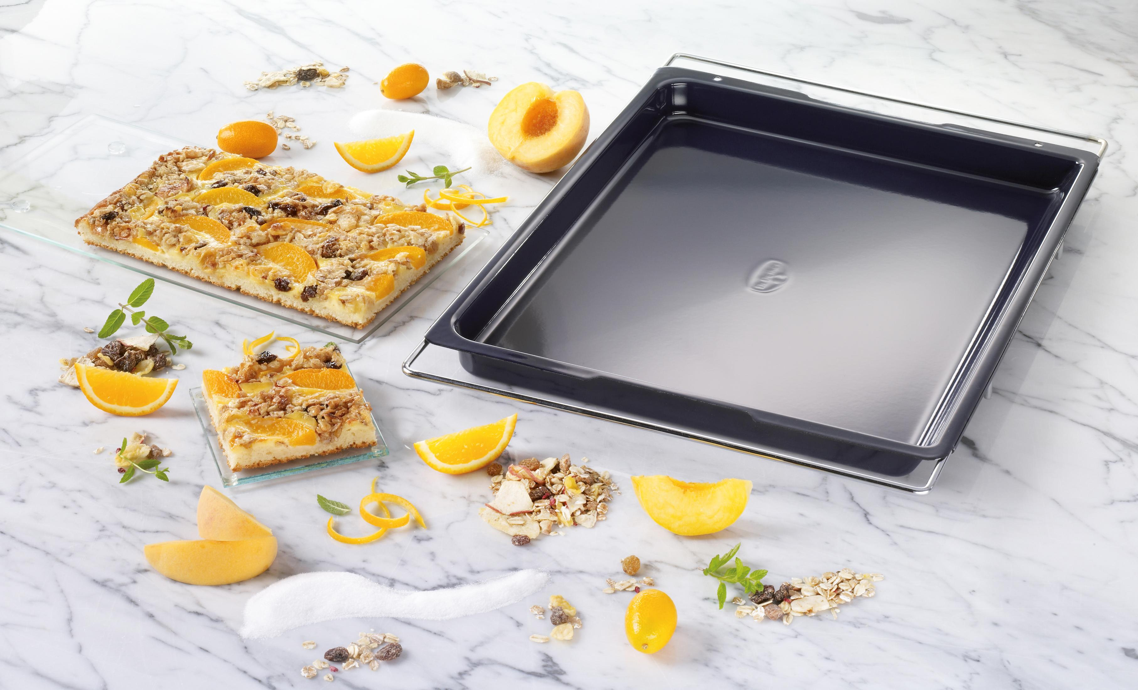 Ein Blechkuchen mit Obst und Nüssen neben einer leeren Backform.