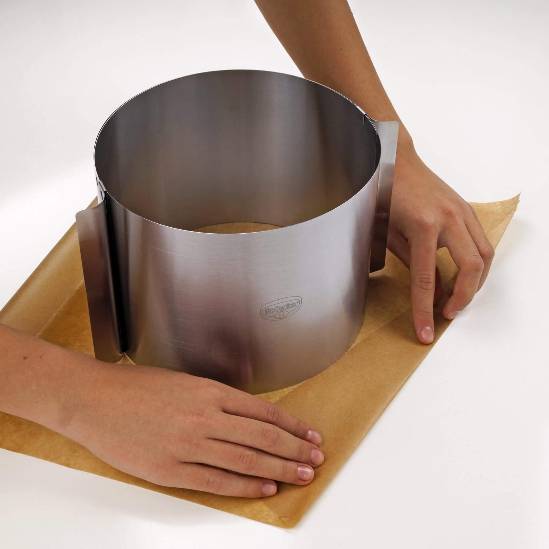 Hände platzieren einen Metallring auf Backpapier.