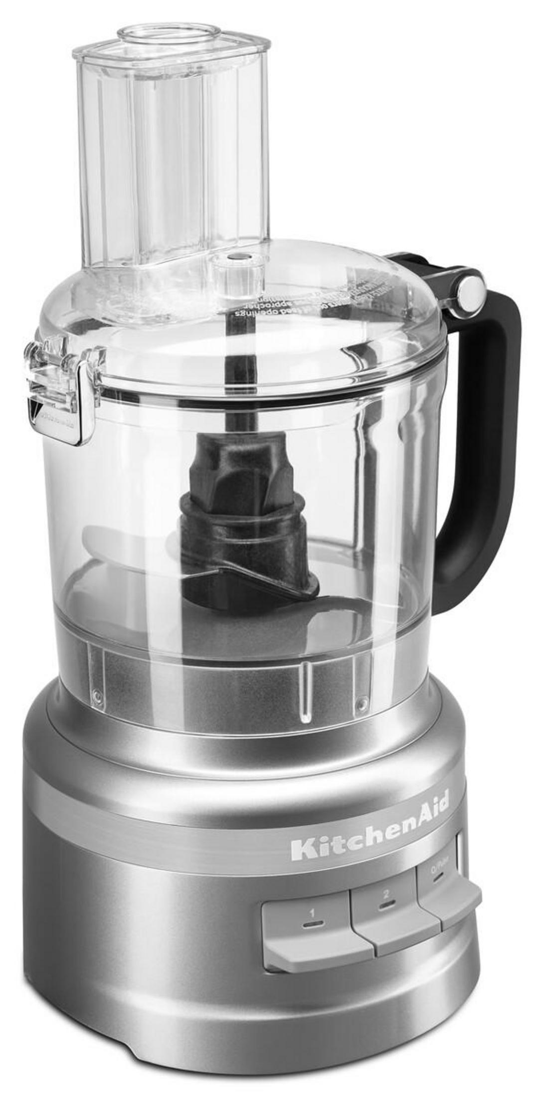 Un robot da cucina argentato con ciotola trasparente e manico nero. Logo KitchenAid.