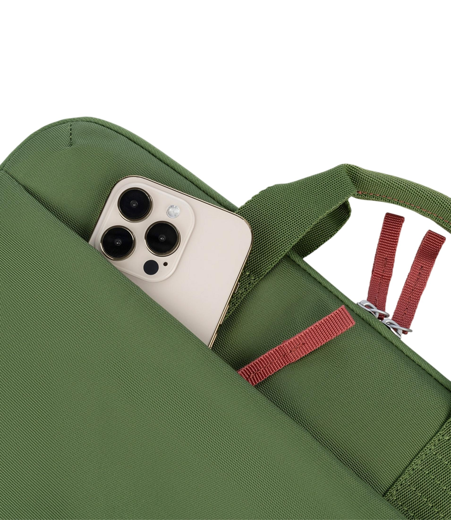 Ein iPhone steckt in einer grünen Tasche mit roten Akzenten.
