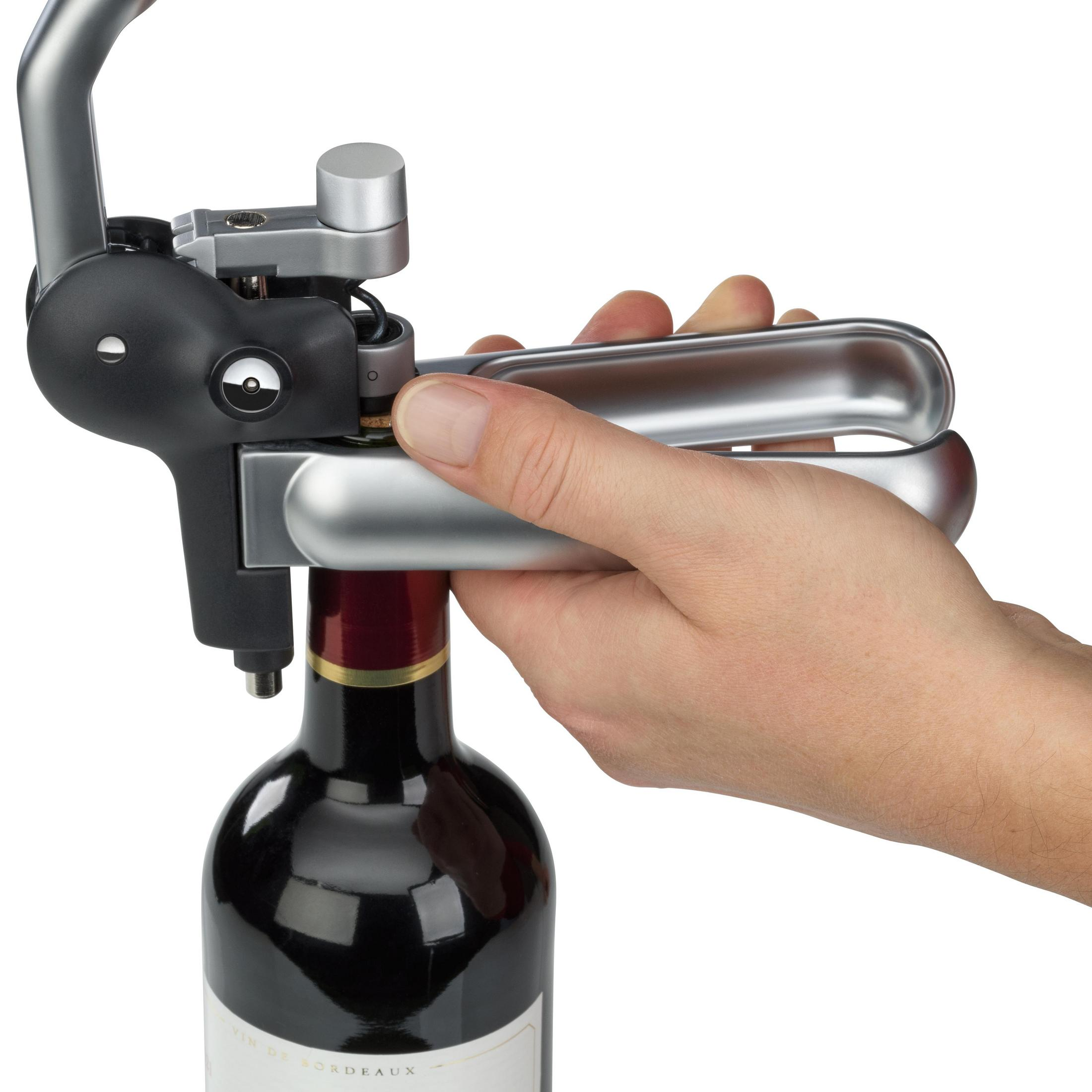 Una mano usa un cavatappi argentato per rimuovere un tappo da una bottiglia di vino.