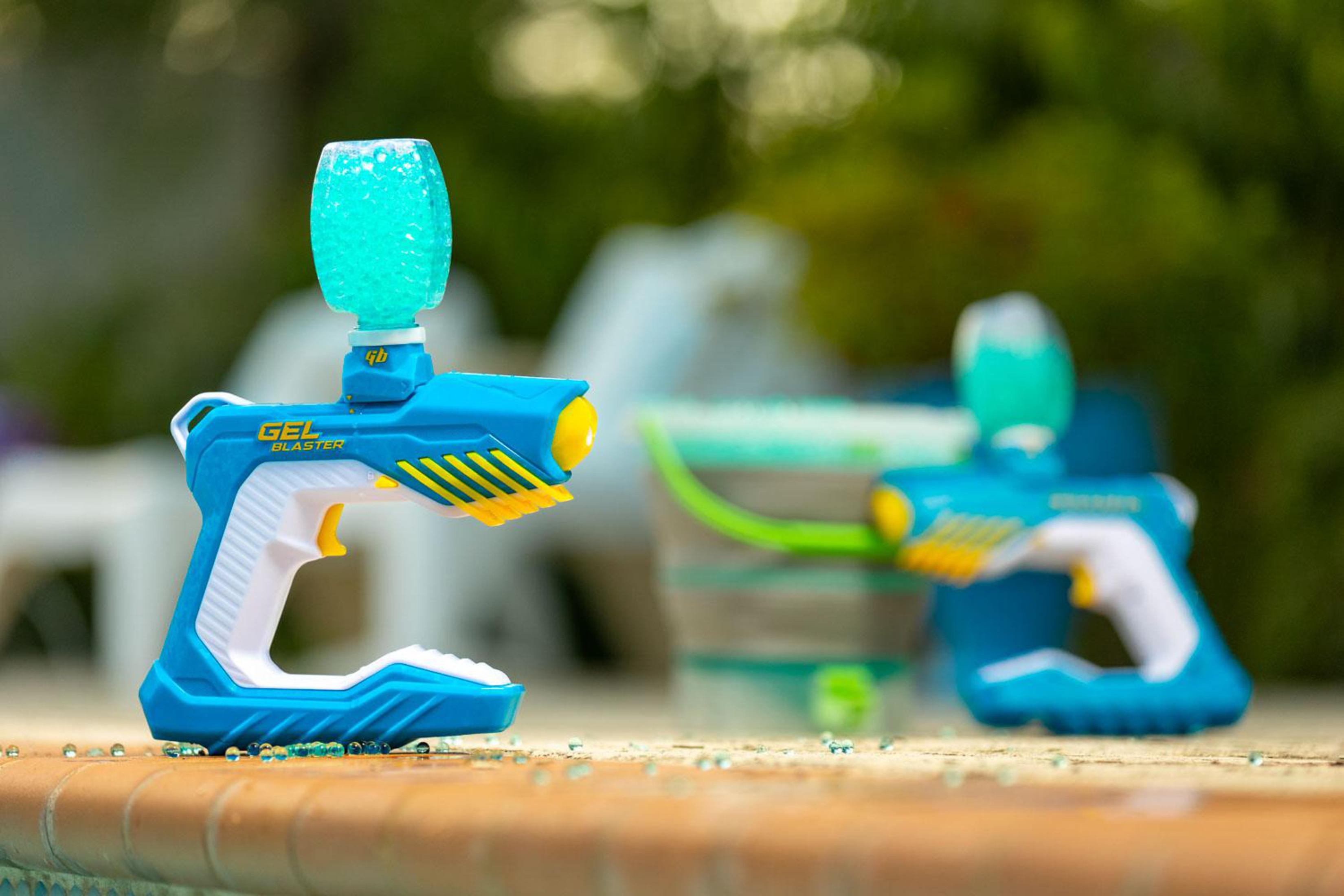 Zwei blaue Gel-Blaster mit Wasserperlen-Magazinen stehen am Poolrand.