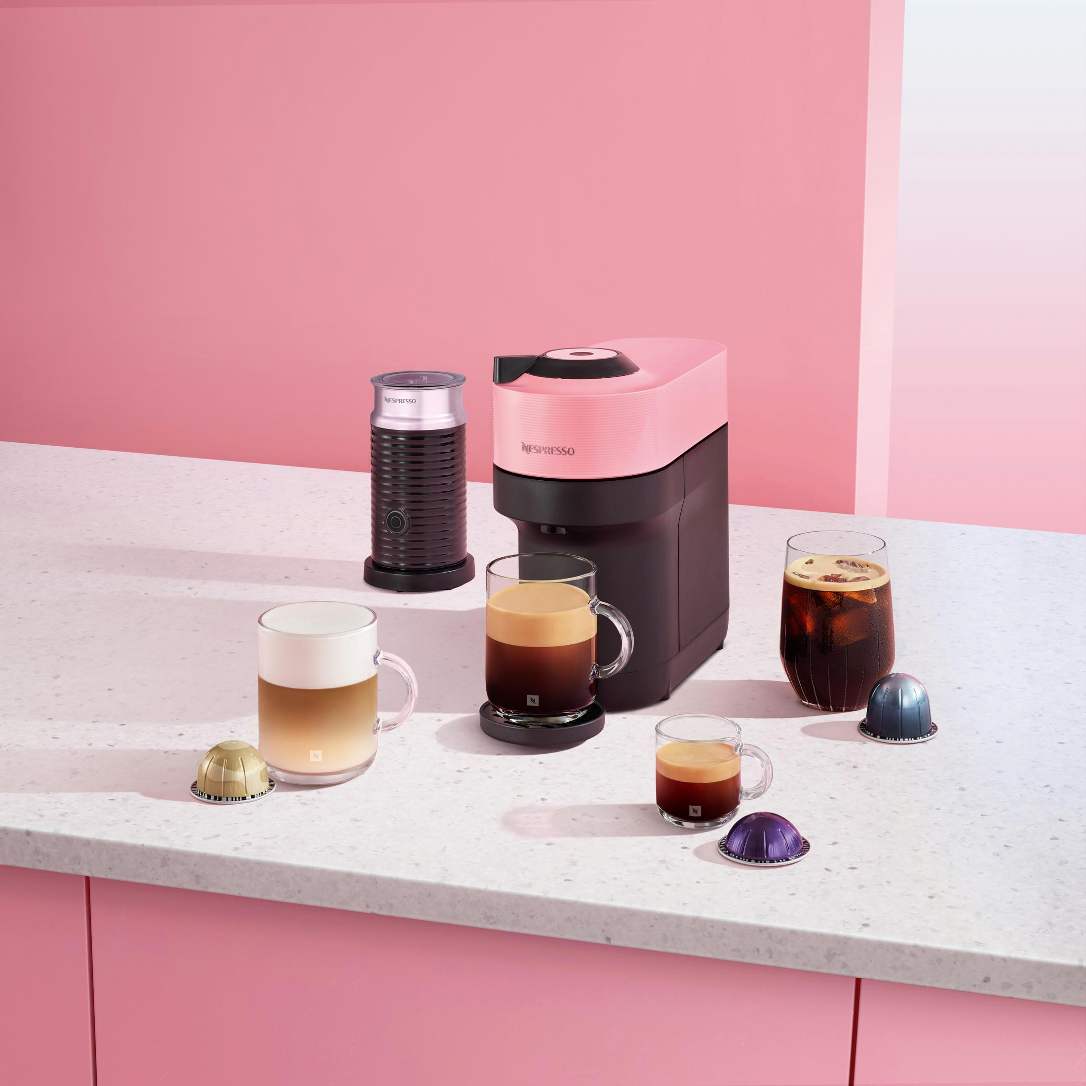 Rosa Nespresso-Maschine, Milchaufschäumer und Kaffeegetränke mit Kapseln.
