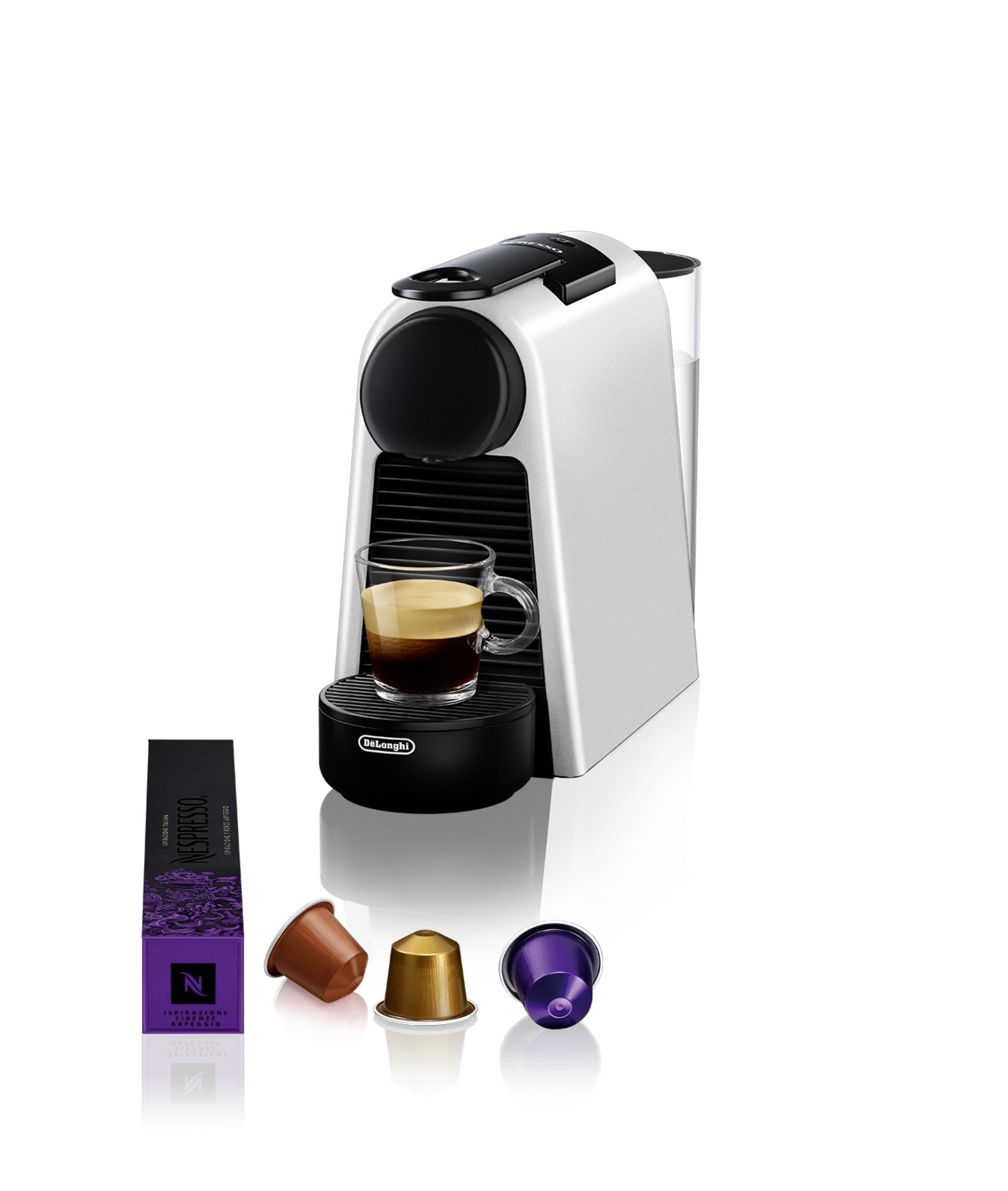 Eine weiße Nespresso-Maschine mit einer Tasse Kaffee, Kapseln und einer Packung.