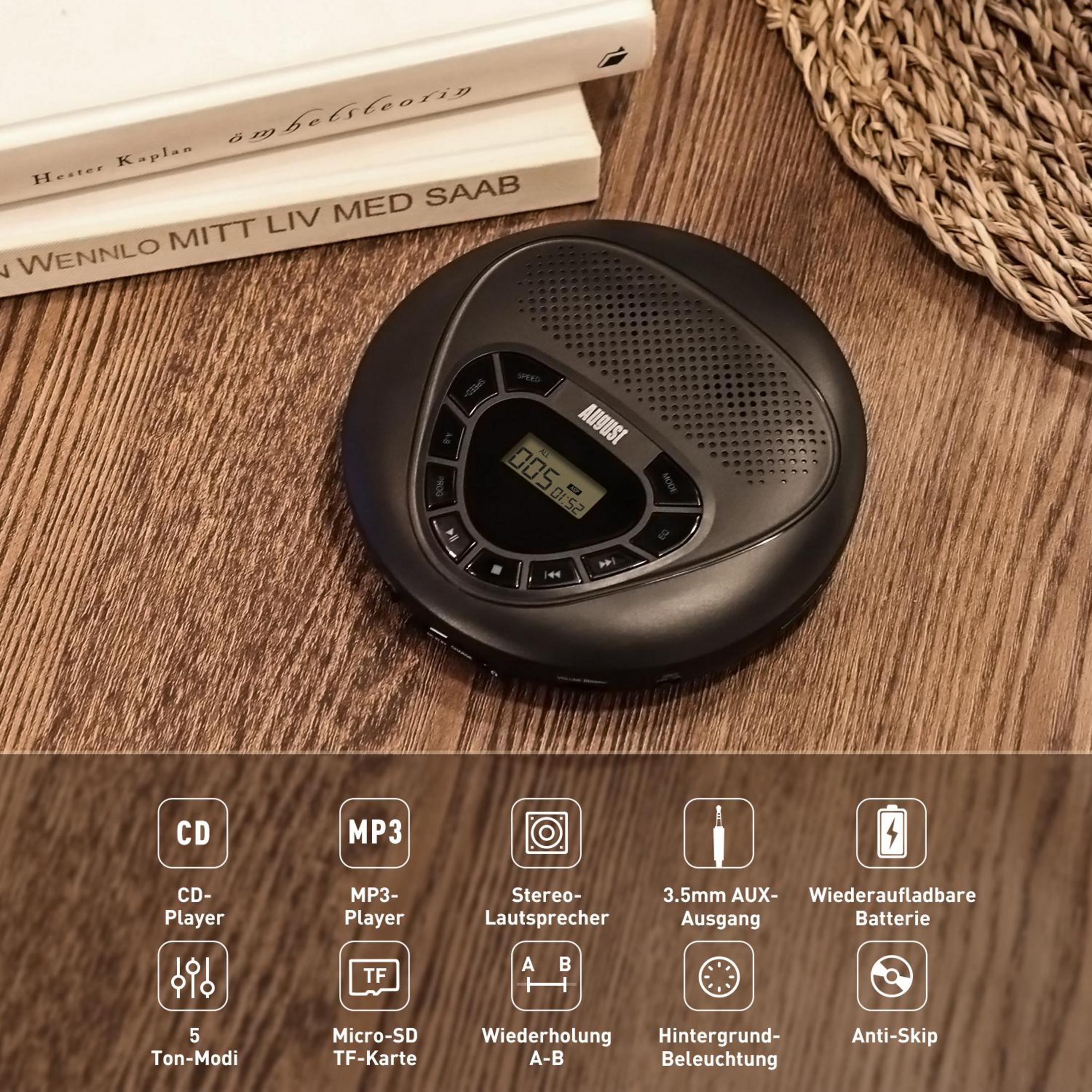 Schwarzer tragbarer CD-Player auf Holztisch mit Büchern und Korb im Hintergrund.