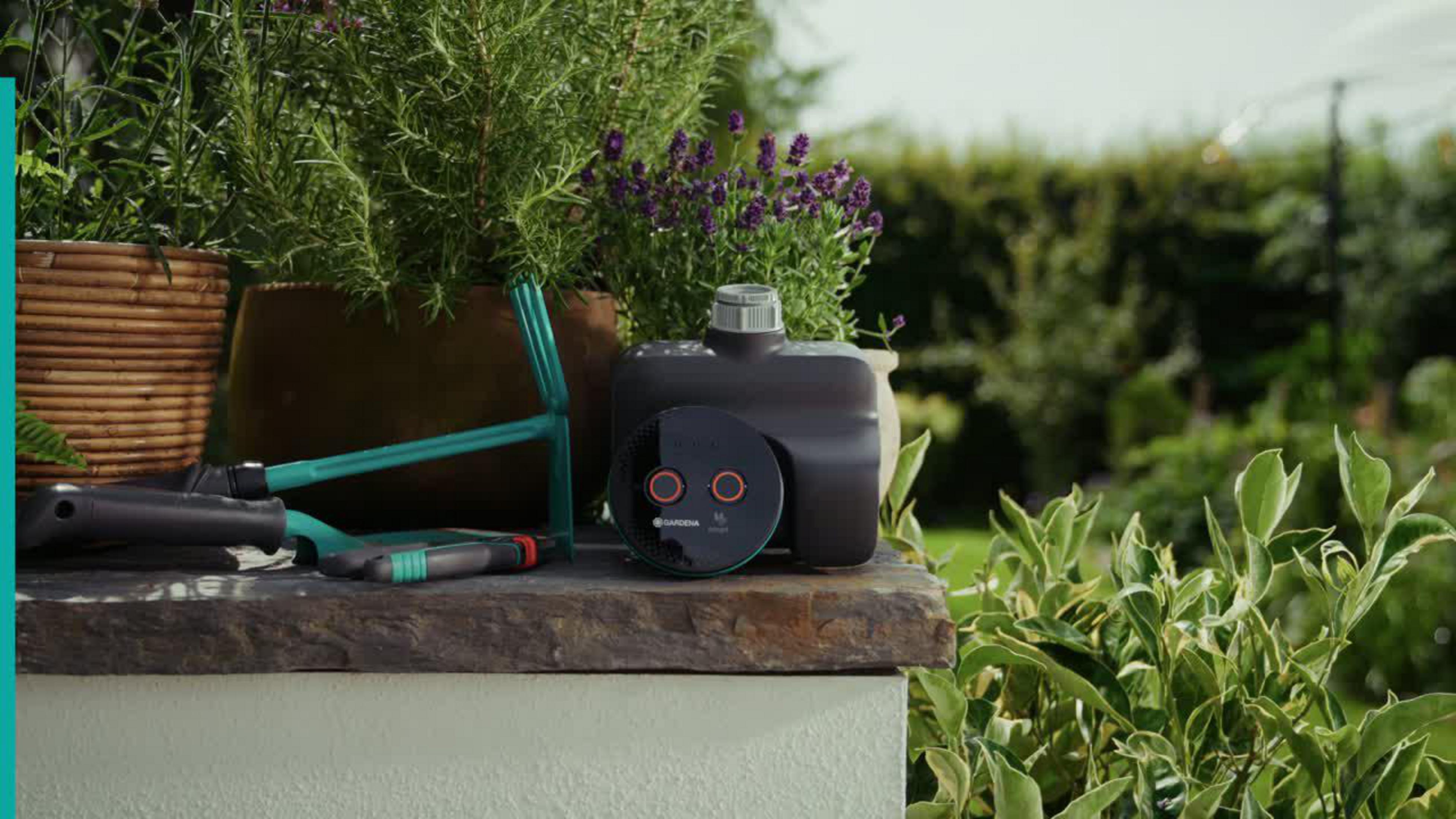 Attrezzi da giardino e un controller per l'irrigazione su uno scaffale di pietra.