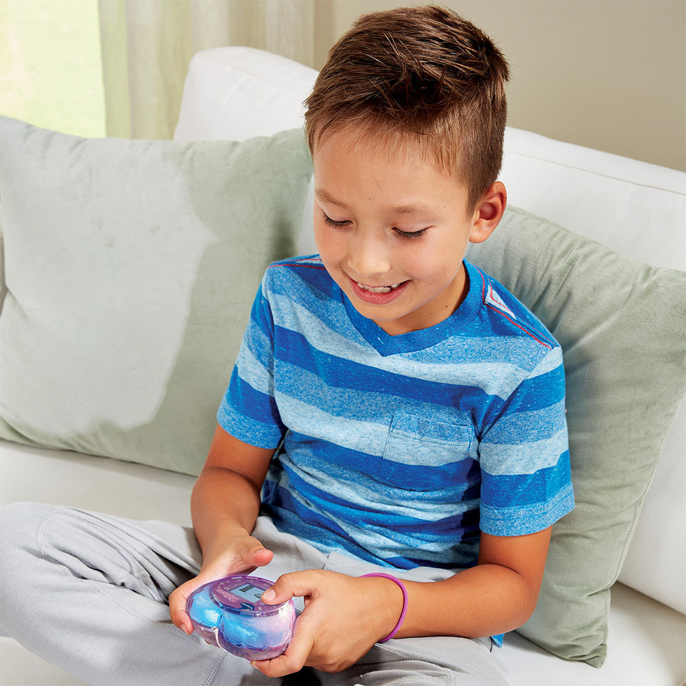 Ein Junge sitzt auf einem Sofa und hält ein leuchtendes Spielzeug in den Händen.