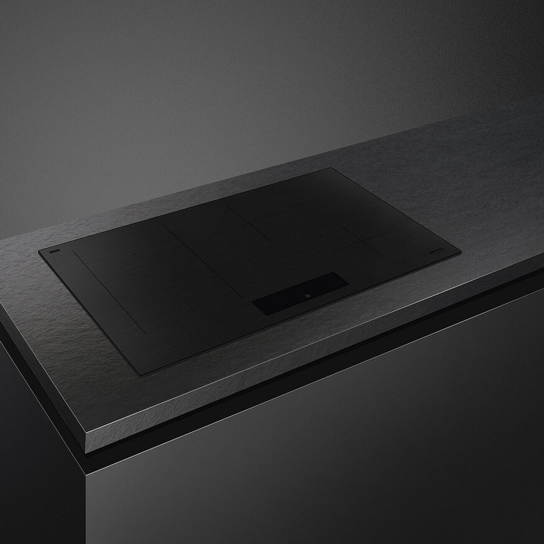 Piano cottura a induzione nero su piano di lavoro scuro.