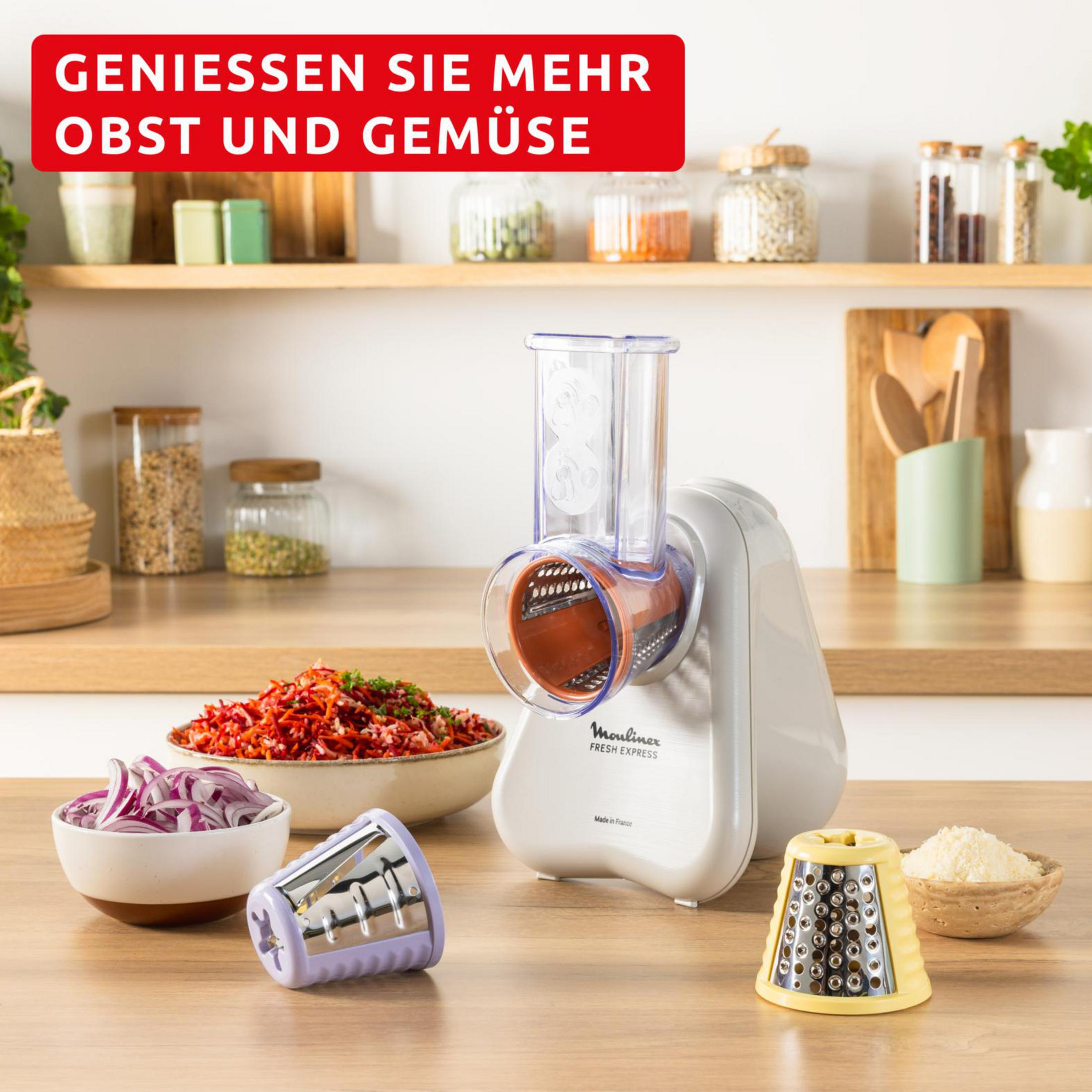 Un robot da cucina bianco con accessori e ciotole di verdure affettate.