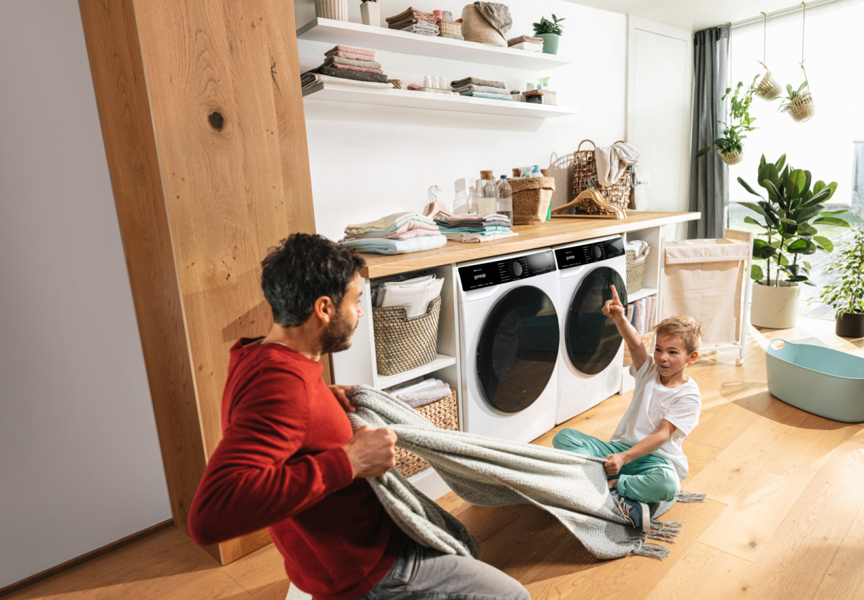 Vater und Sohn mit Decke in Waschküche mit zwei Maschinen.