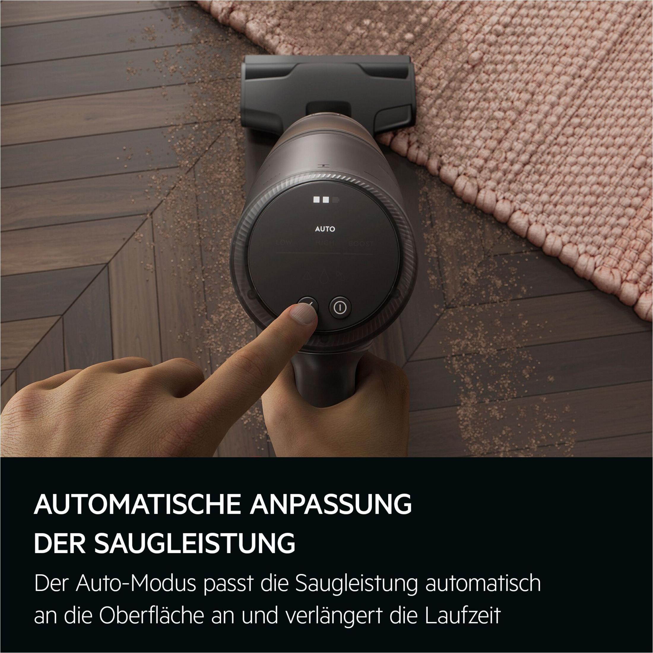 Ein Finger drückt auf den "Auto"-Modus eines Staubsaugers auf Holz und Teppich.