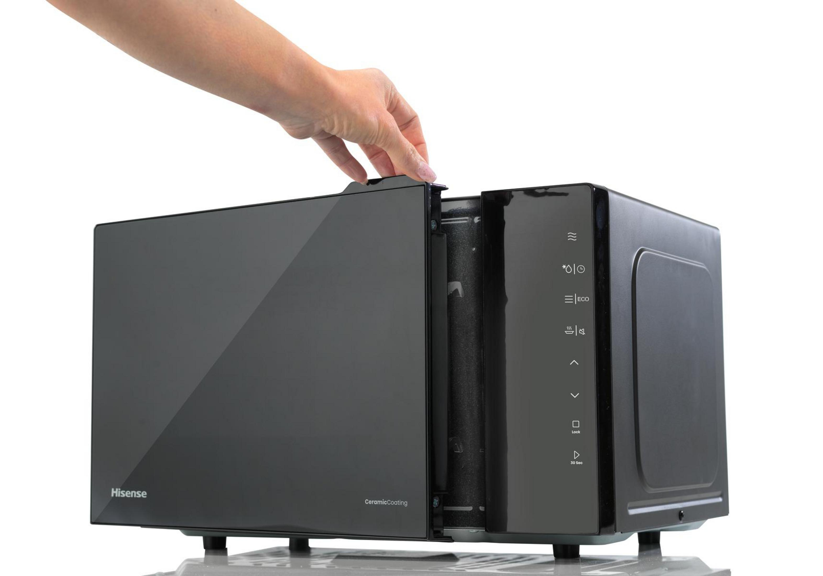 Una mano abre un microondas negro con puerta de cristal y panel táctil.