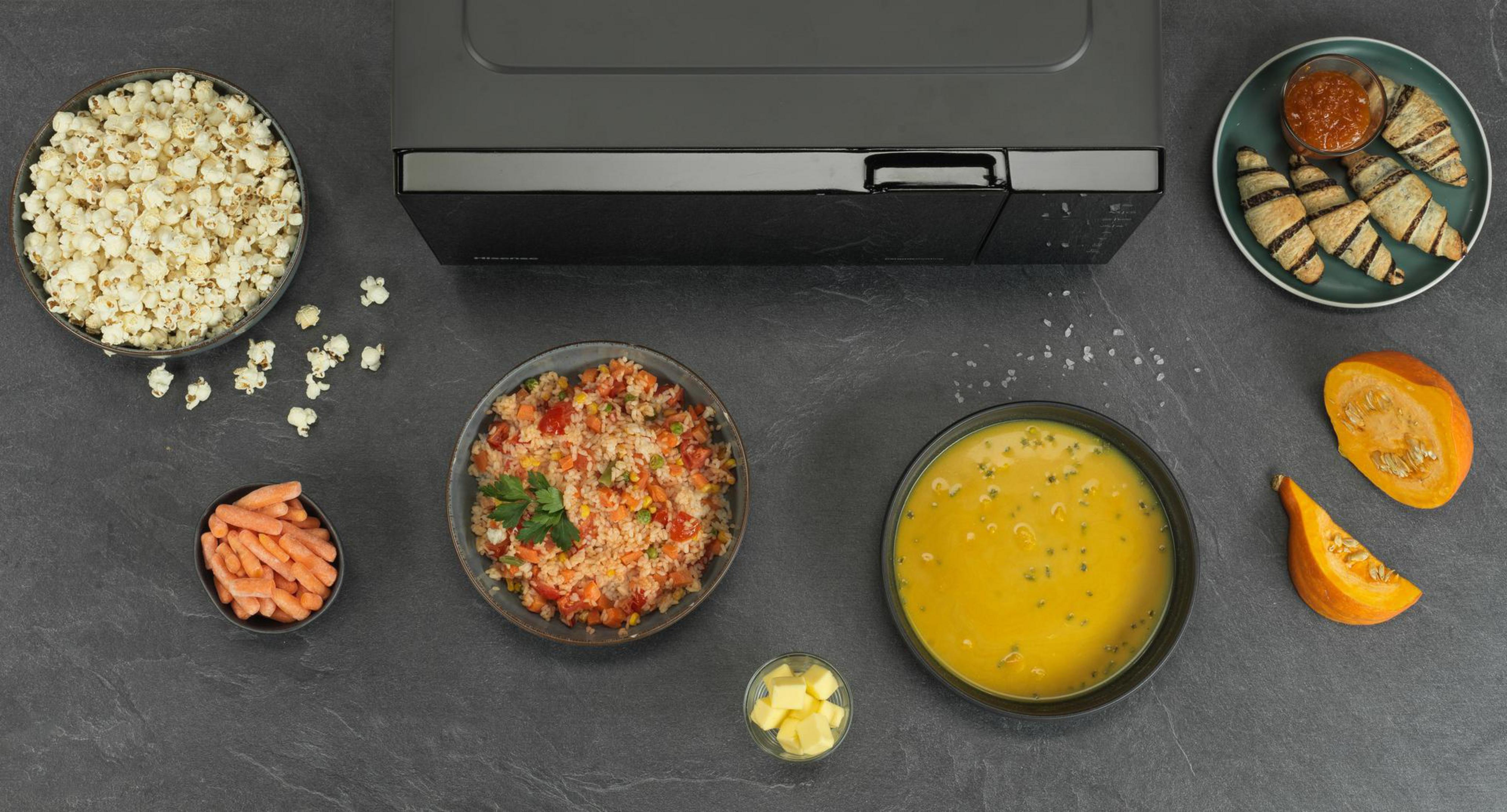 Vista aérea de alimentos que incluyen palomitas de maíz, zanahorias, arroz, sopa y croissants.