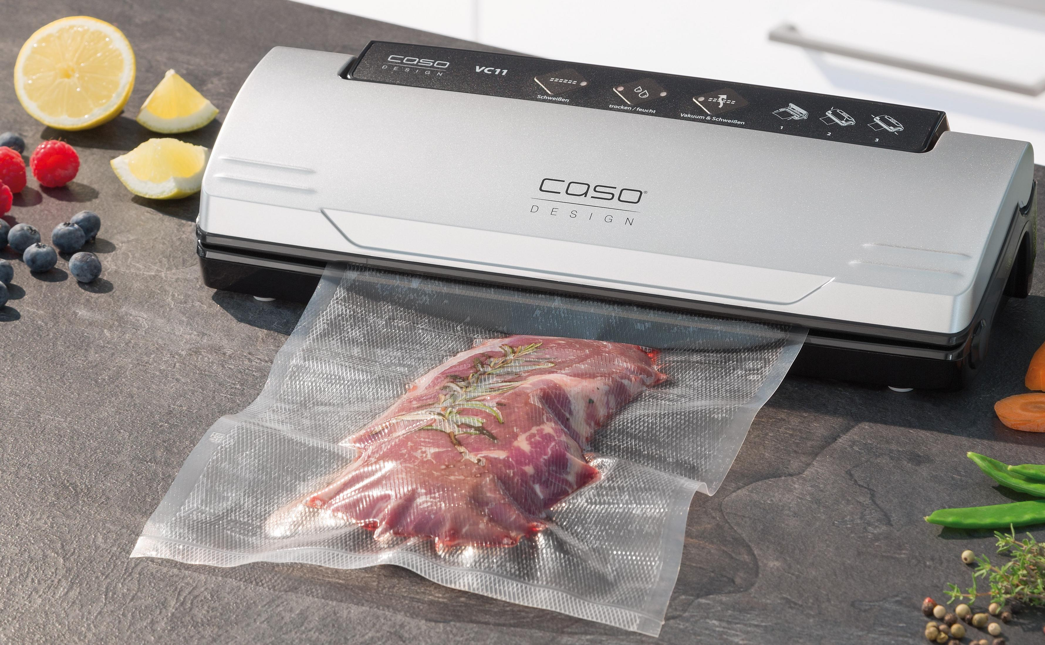 Ein Vakuumiergerät versiegelt Fleisch in einem Plastikbeutel neben Obst.