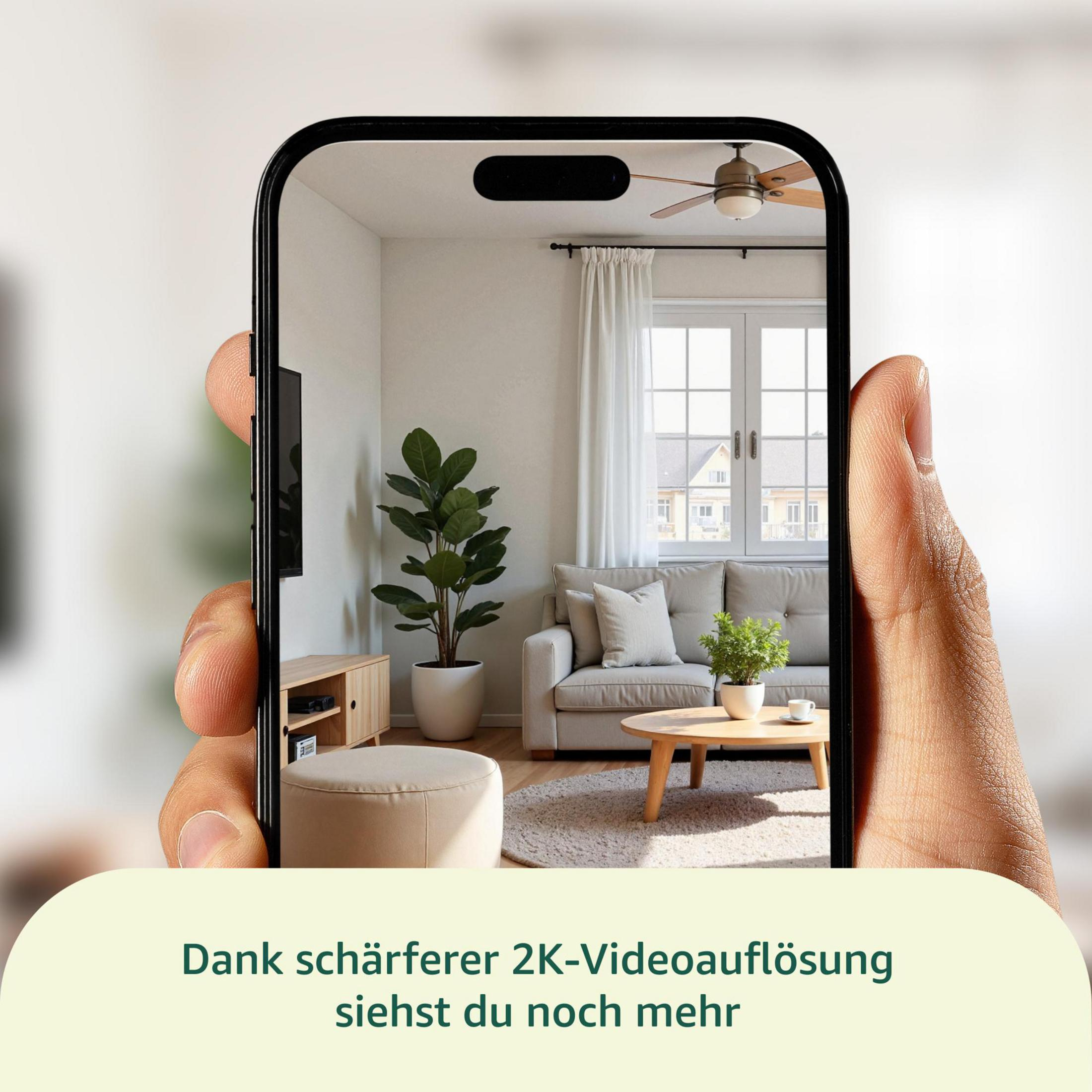 Uno smartphone mostra un soggiorno con divano, tavolino e pianta.
