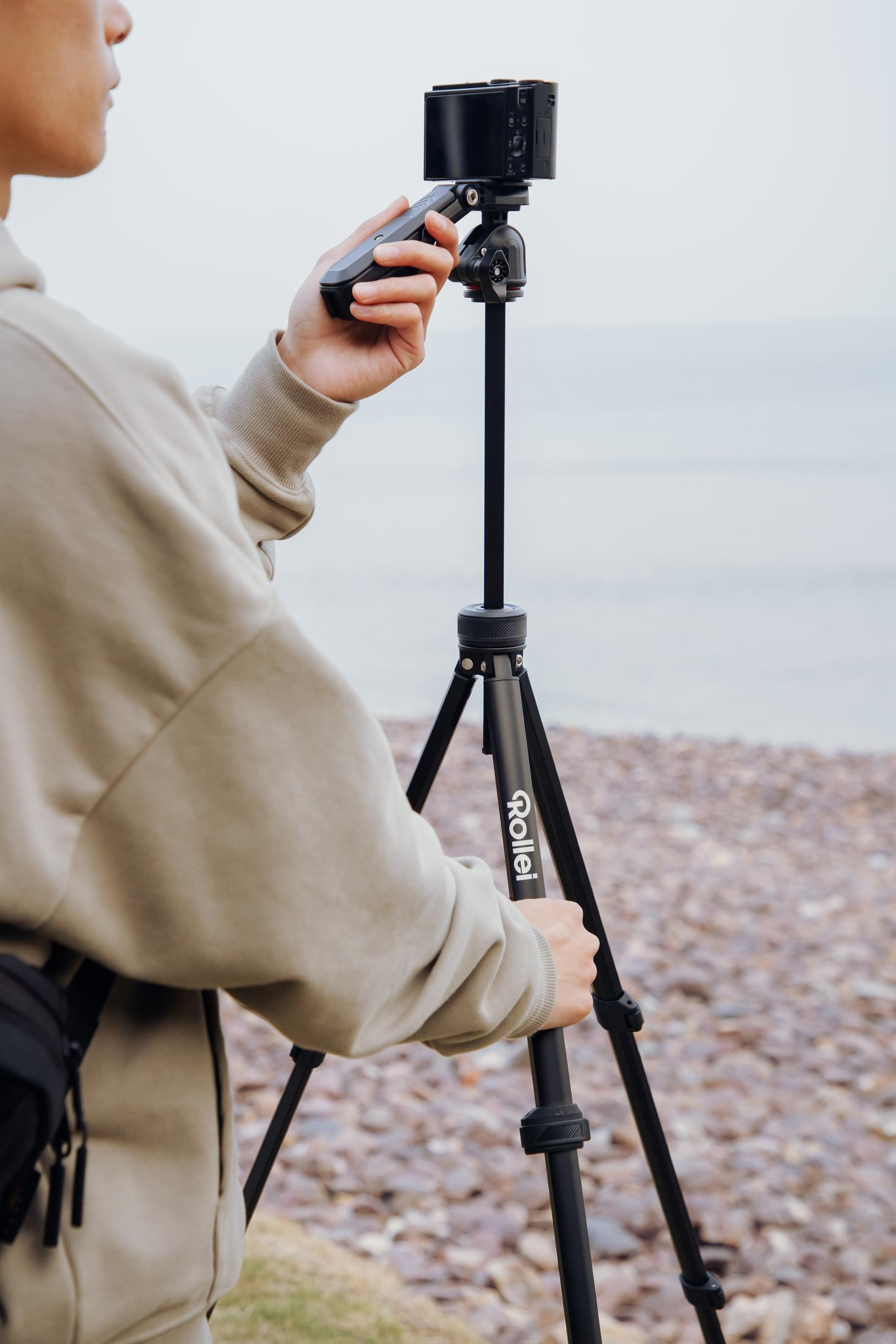 Una persona regola una fotocamera su un treppiede vicino all'acqua.