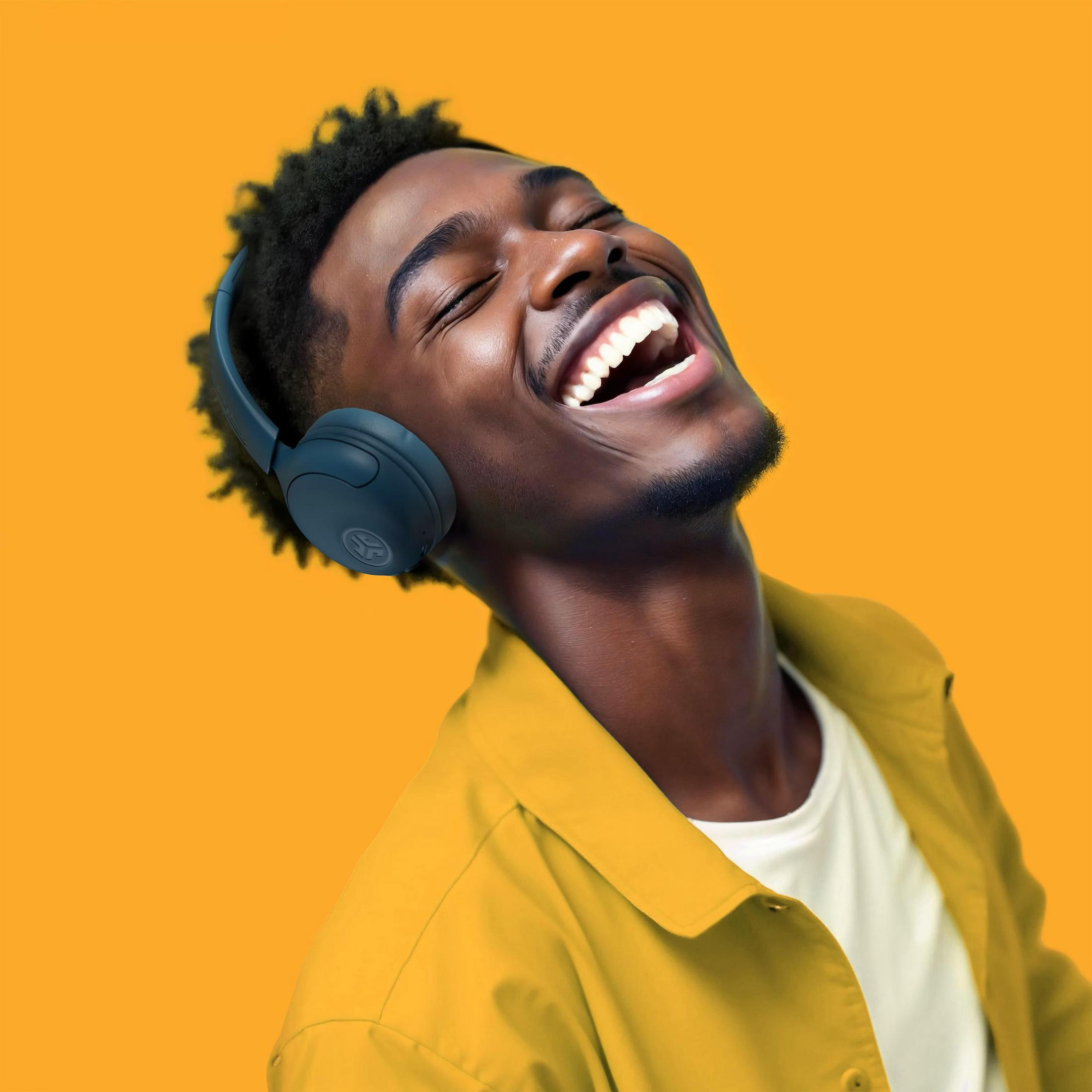 Un jeune homme portant un casque rit sur fond orange.