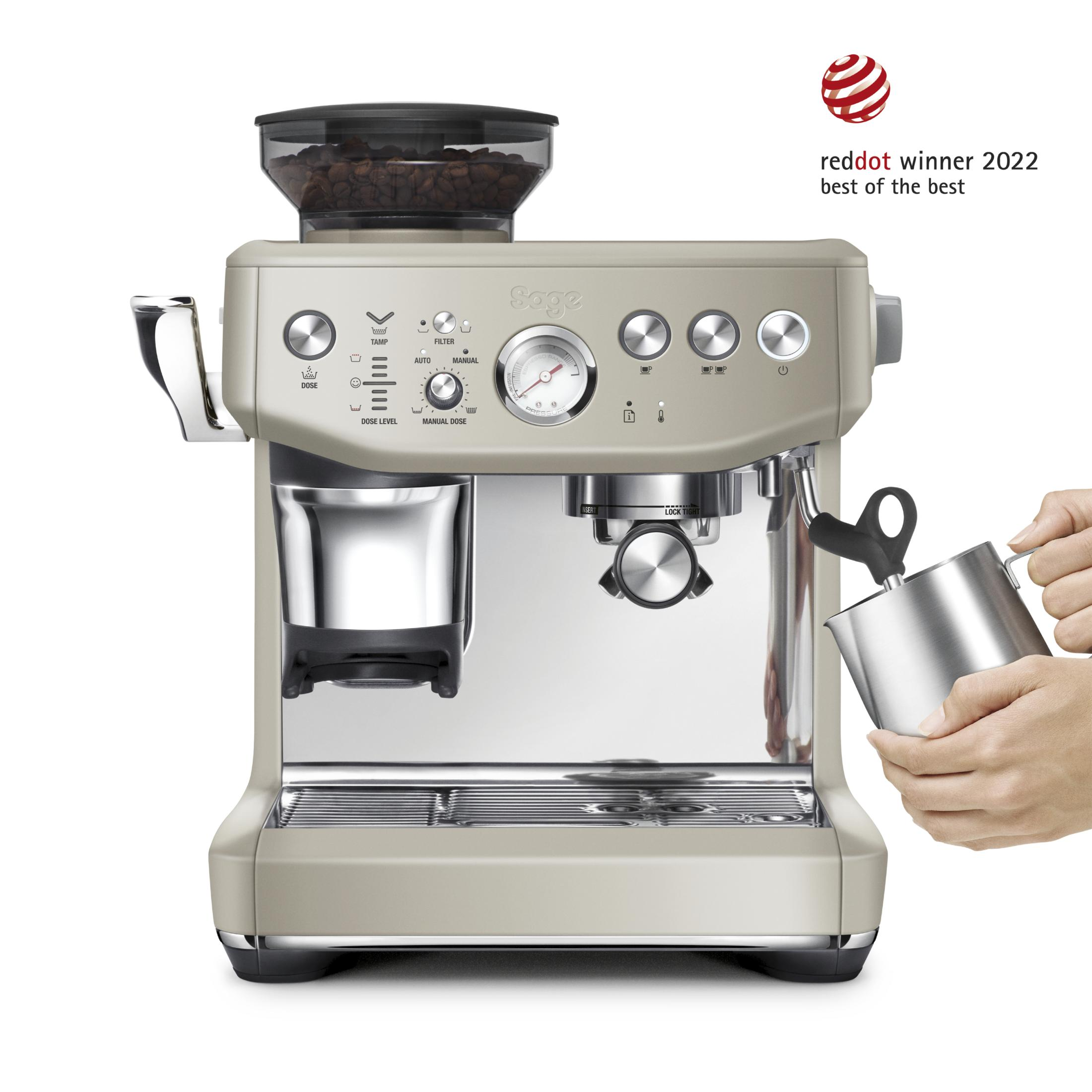 Eine beige Espressomaschine mit Kaffeebohnenbehälter. Eine Hand hält eine Milchkanne.