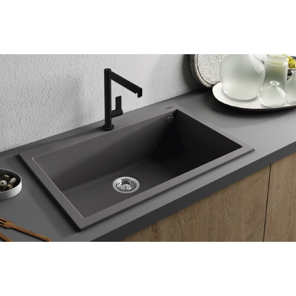 Un lavello grigio scuro con rubinetto nero su un piano di lavoro grigio.