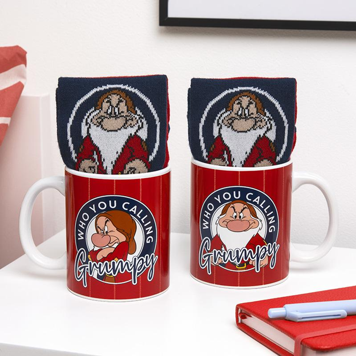 Dos tazas rojas con rayas blancas, con Gruñón de Blancanieves. Hay calcetines dentro.