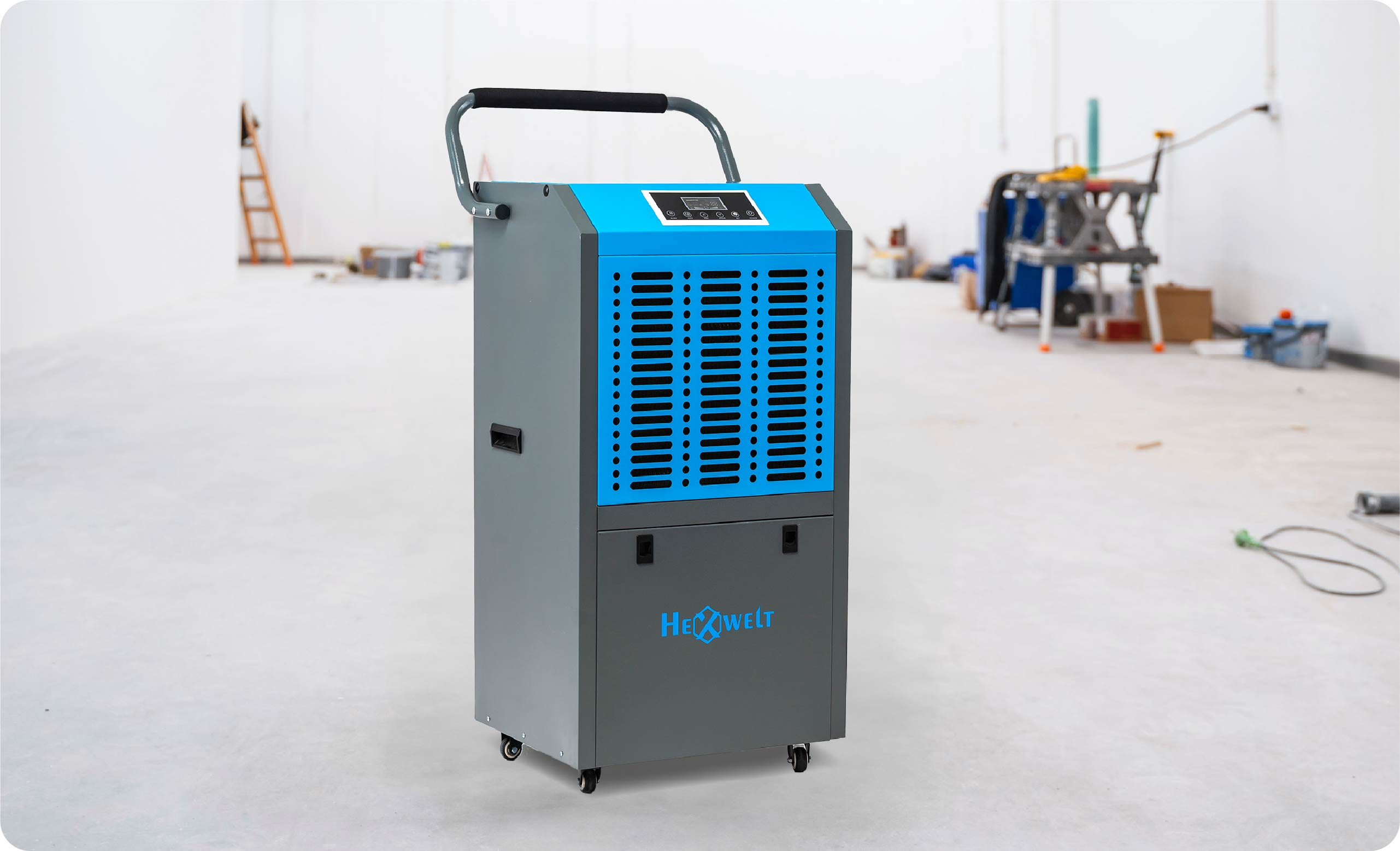 Niebieski i szary osuszacz na kółkach w pustym pomieszczeniu z narzędziami.