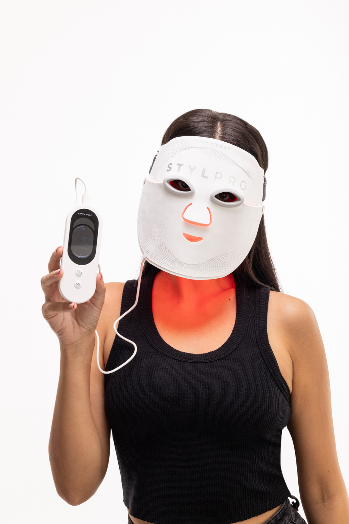 Una donna indossa una maschera facciale LED bianca e tiene un dispositivo di controllo.