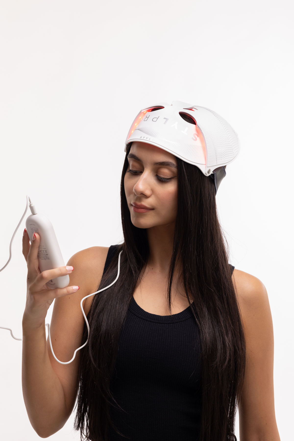 Donna con lunghi capelli scuri indossa una maschera LED bianca, tenendo un dispositivo di controllo.