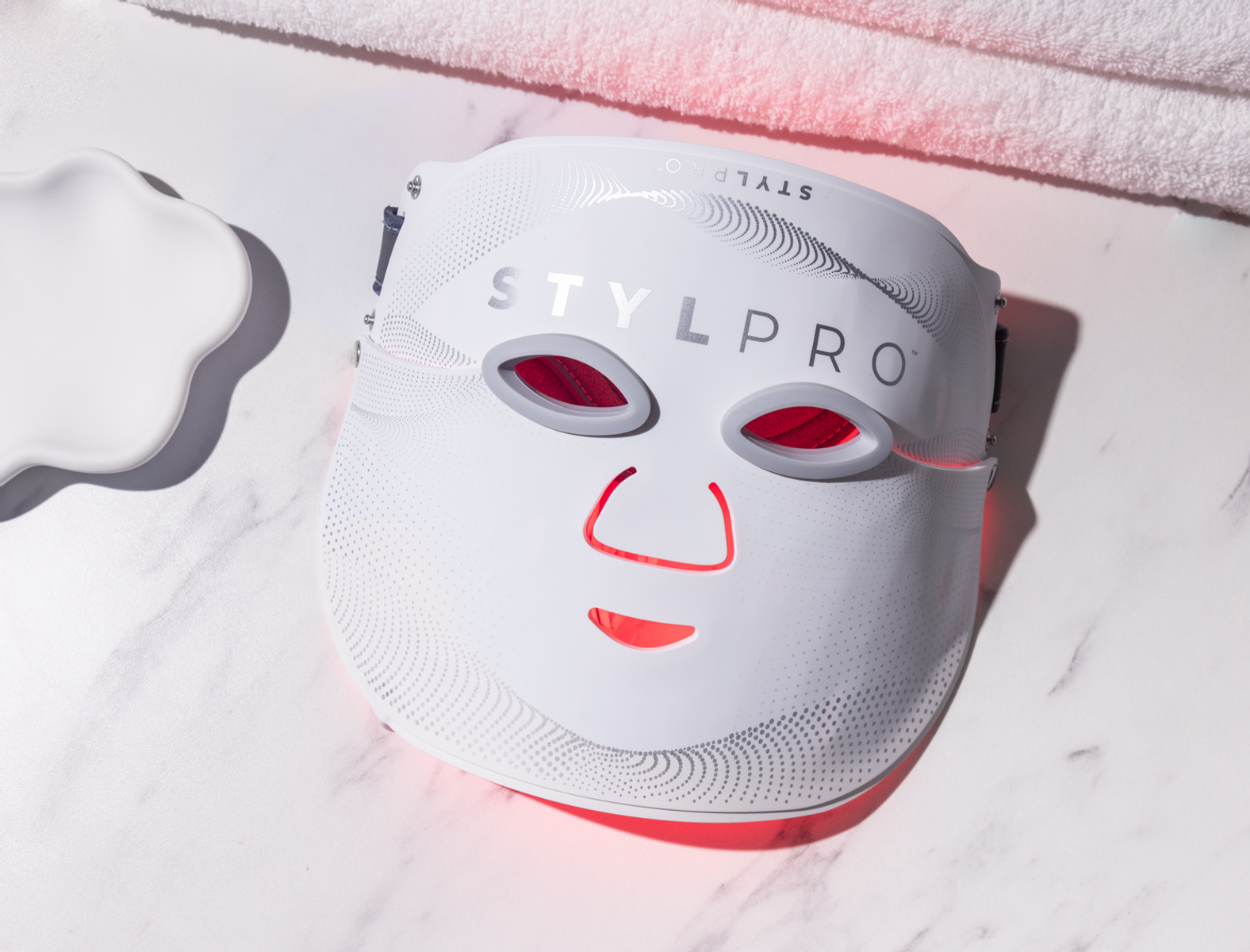 Maschera viso LED bianca con luci rosse per occhi e bocca, su marmo.