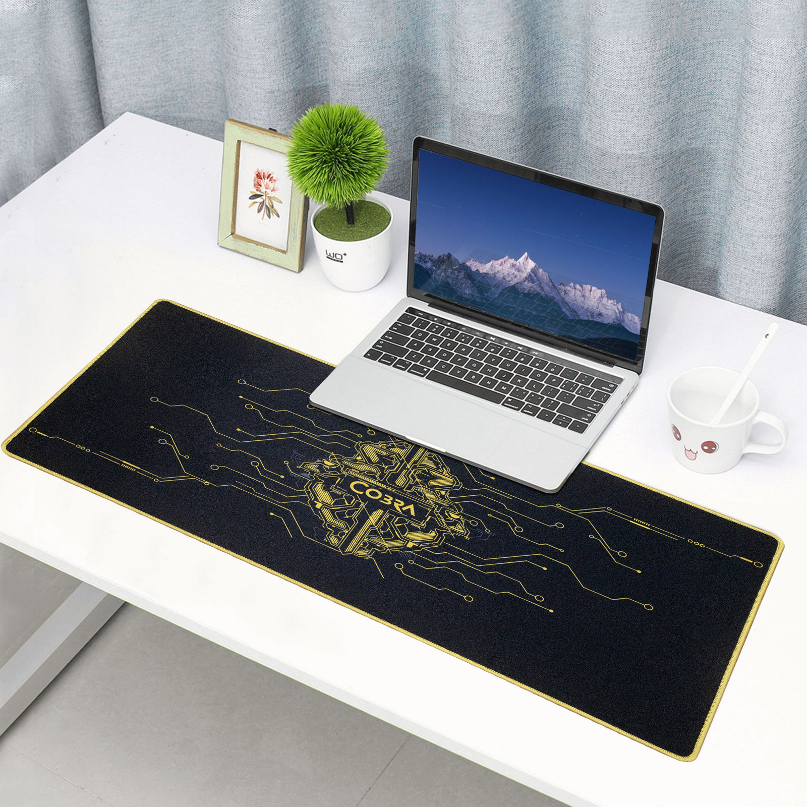 Laptop na czarnej podkładce pod mysz z żółtym wzorem obwodu drukowanego.