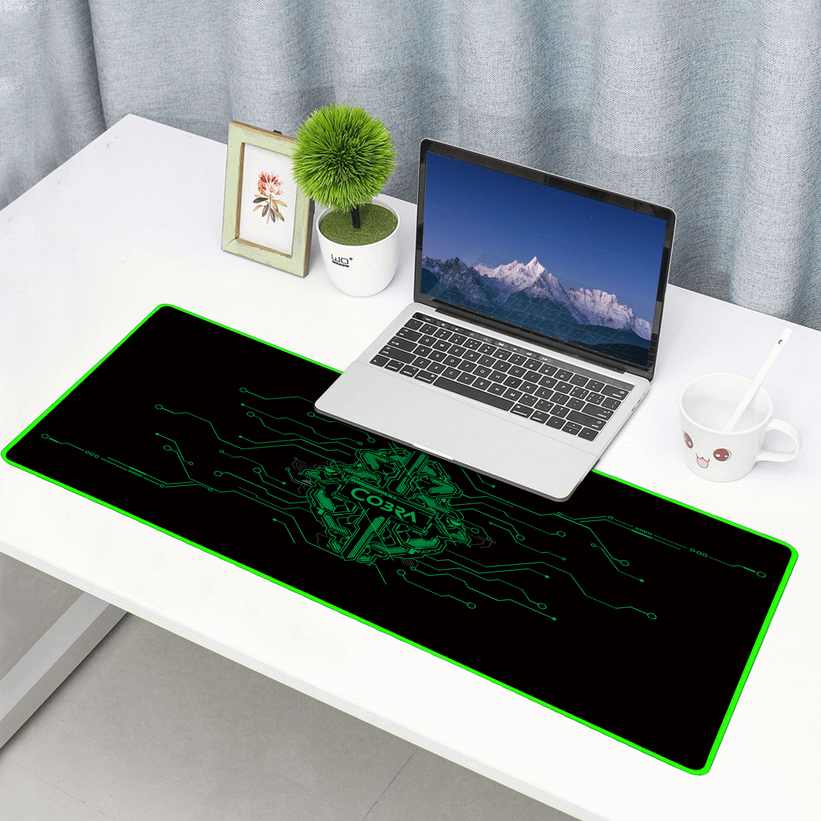 Laptop stoi na czarnej podkładce pod mysz z zielonymi wzorami obwodów.