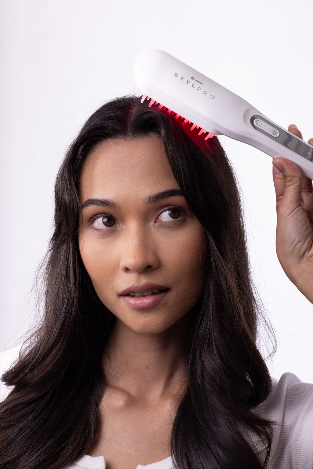 Una donna usa un pettine laser bianco con luci rosse sulla testa.