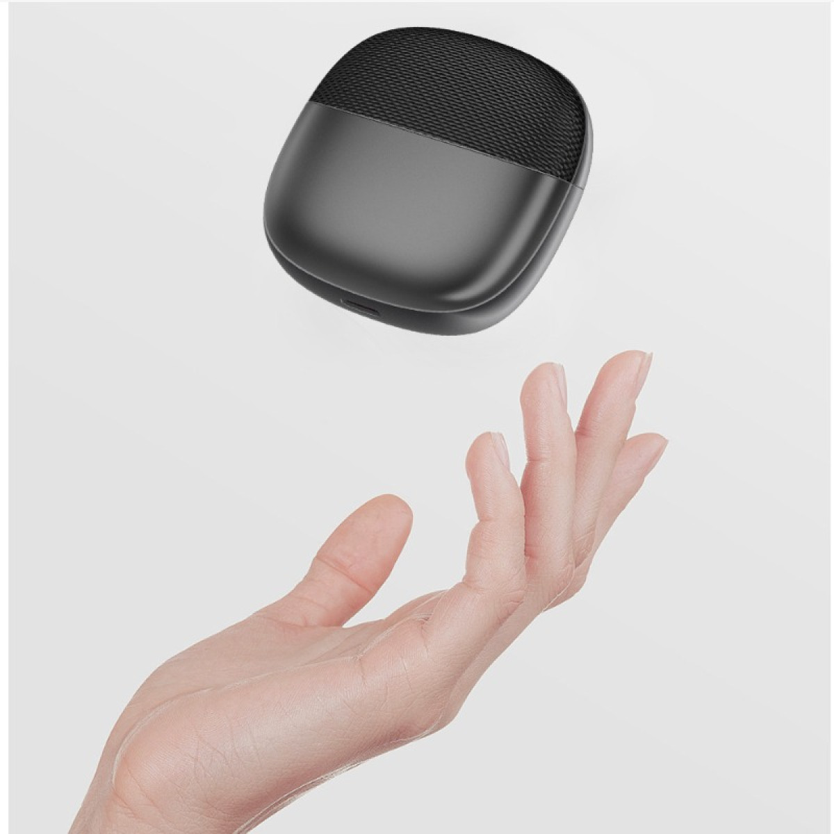 Czarna ładowarka do słuchawek bezprzewodowych unosi się nad otwartą dłonią.