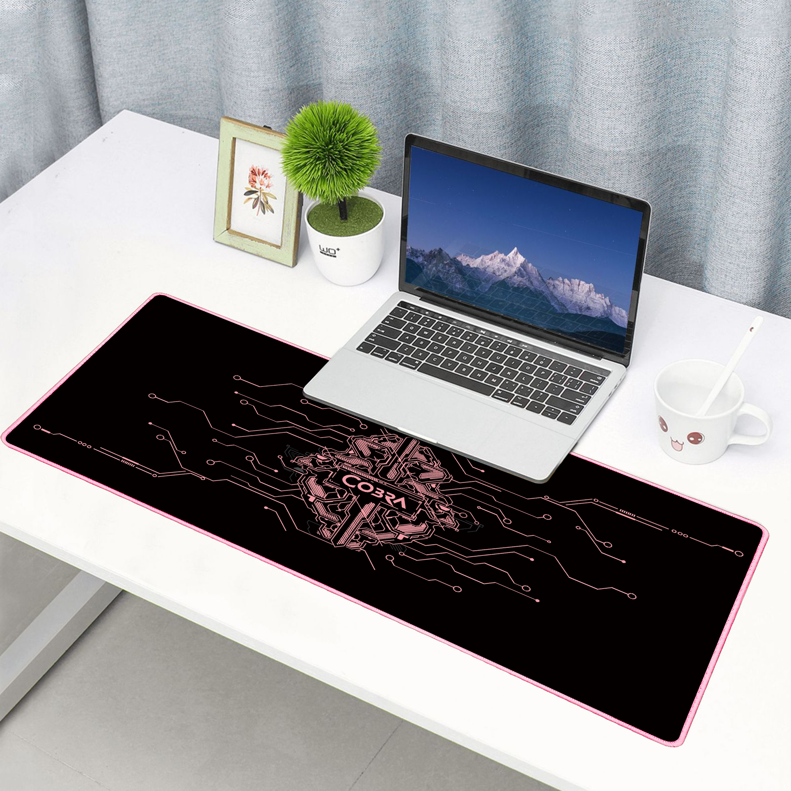 Laptop na biurku z dużą czarną podkładką pod mysz z różowymi liniami obwodów.