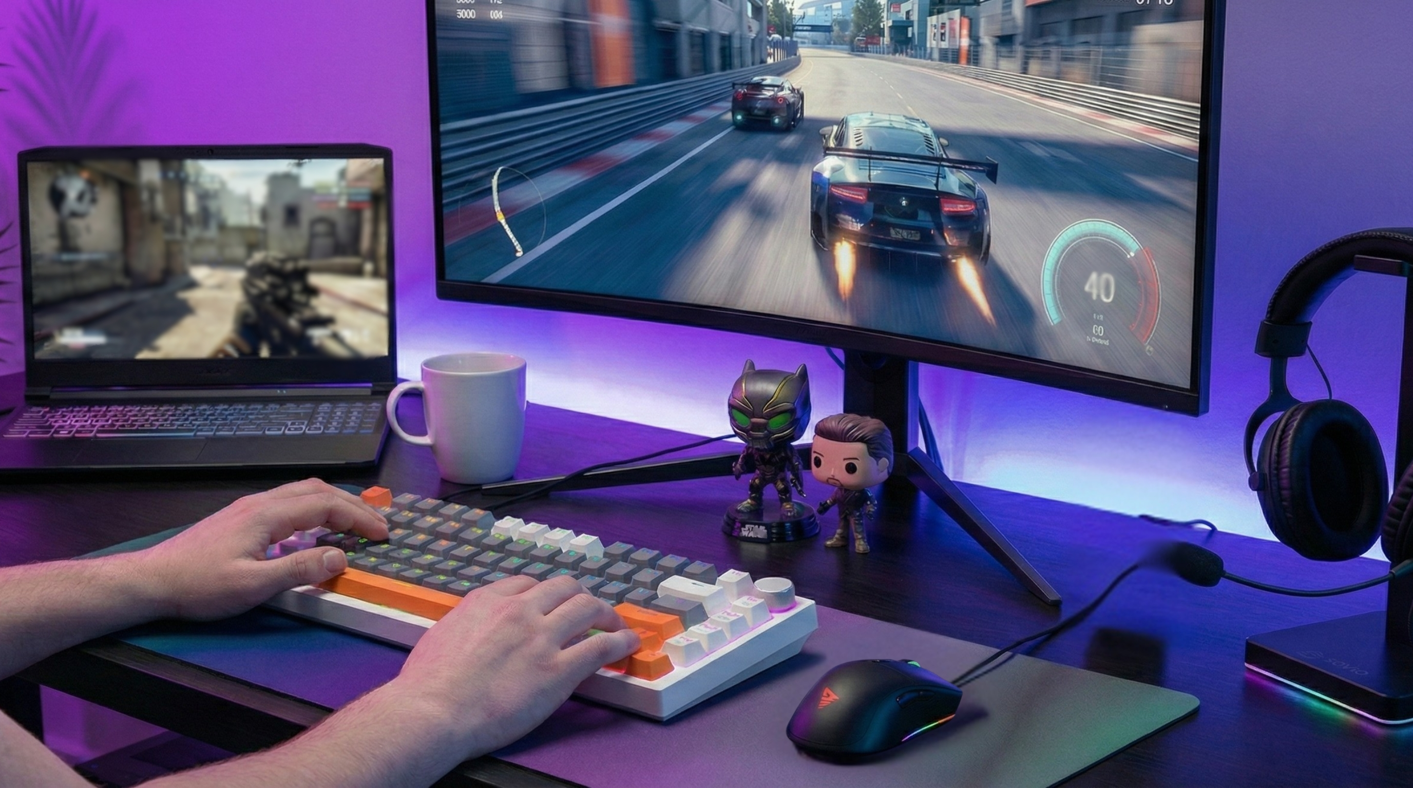 Dłonie na klawiaturze grające w grę wyścigową na monitorze i strzelankę na laptopie.