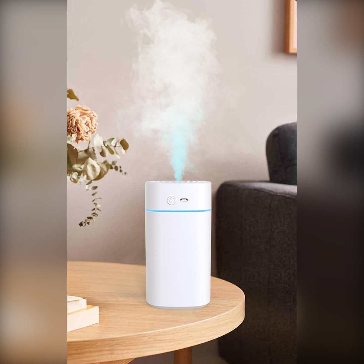 Biały nawilżacz wypuszcza niebieskawą mgiełkę na drewnianym stole.