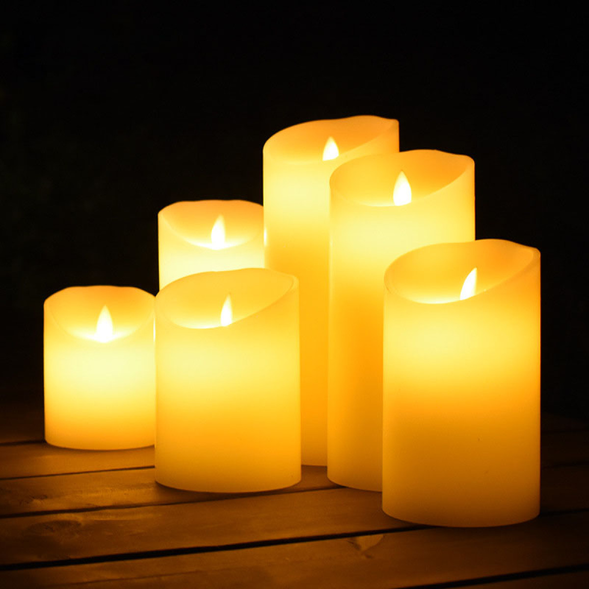 Cinq bougies LED sur table en bois dans le noir, lumière chaude.