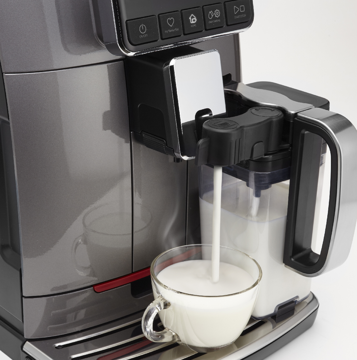 Il latte viene versato in una tazza di vetro da una macchina da caffè.