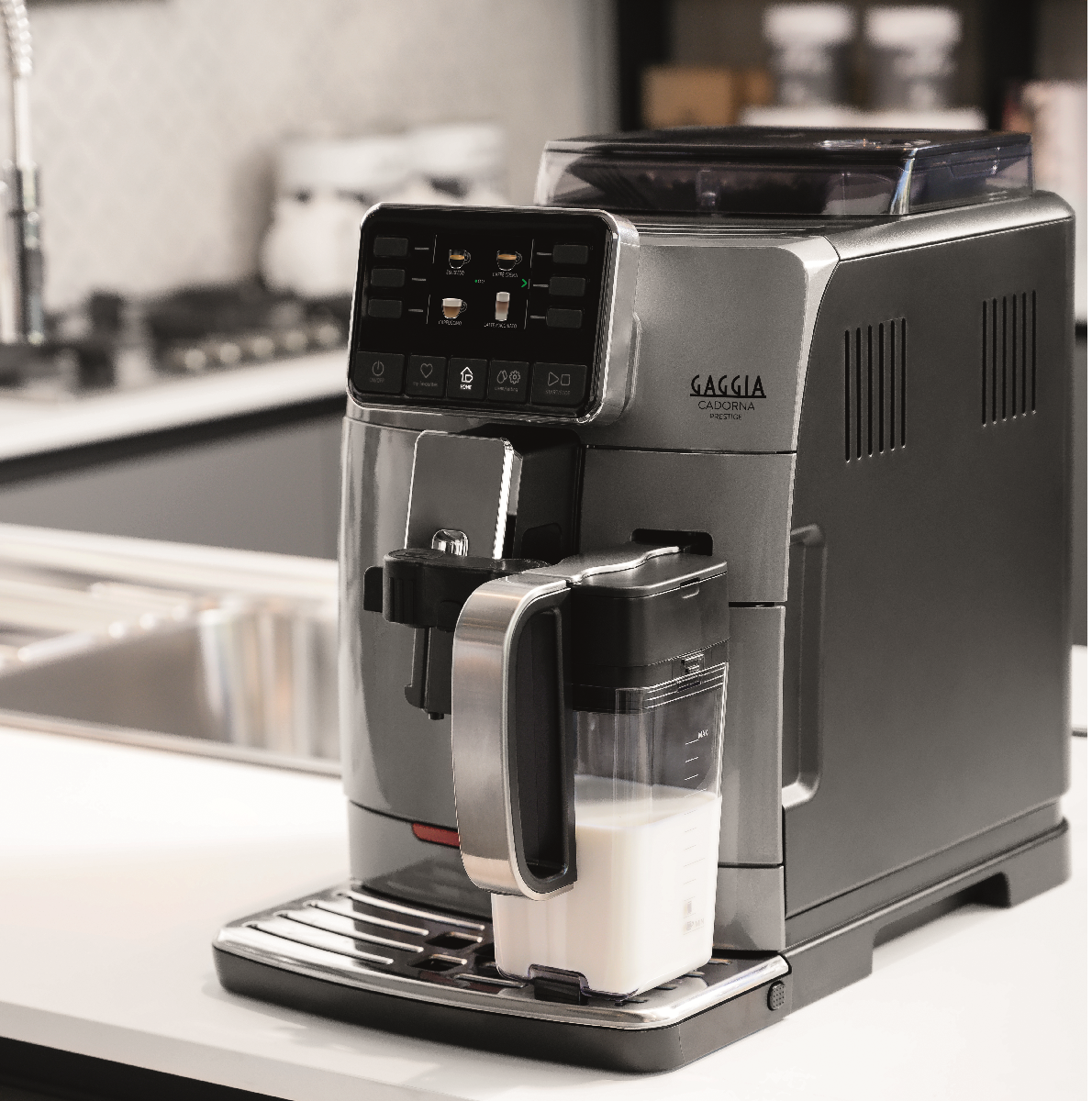 Una macchina da caffè Gaggia Cadorna Prestige argentata con caraffa per il latte su un piano di lavoro bianco.