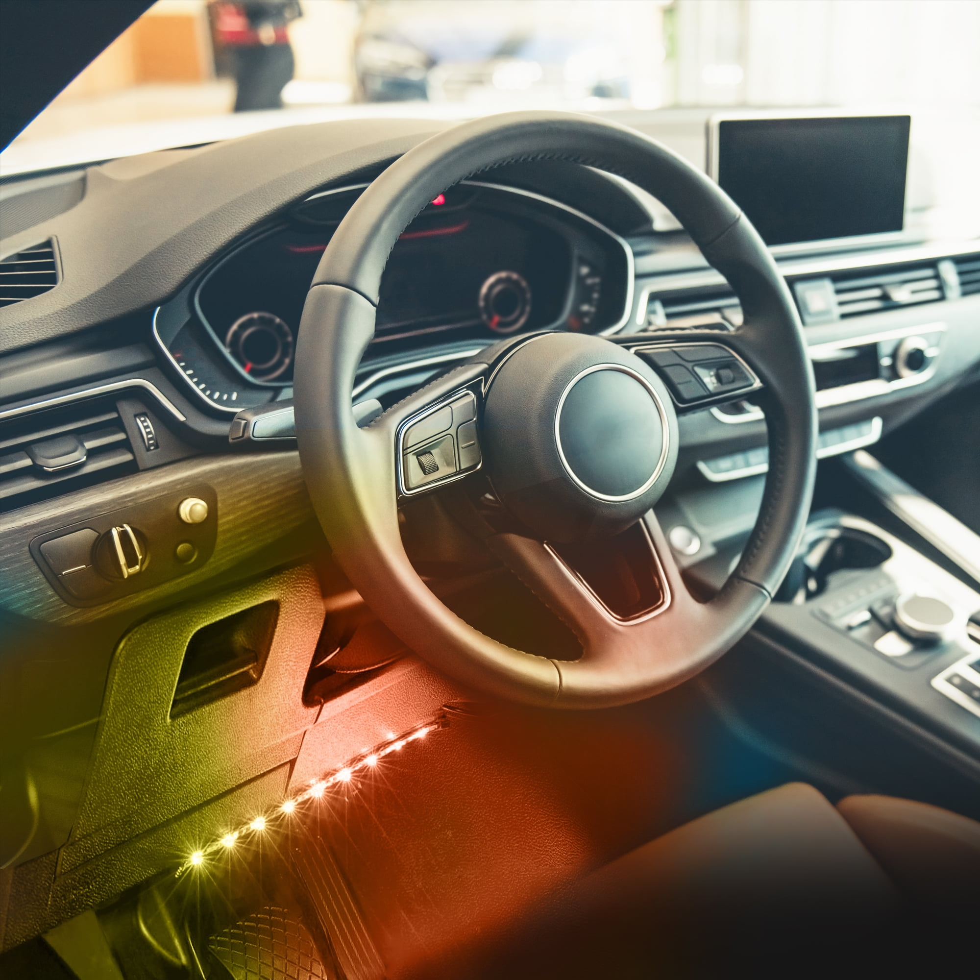 Autoinnenraum mit Lenkrad, Armaturenbrett und Umgebungsbeleuchtung.