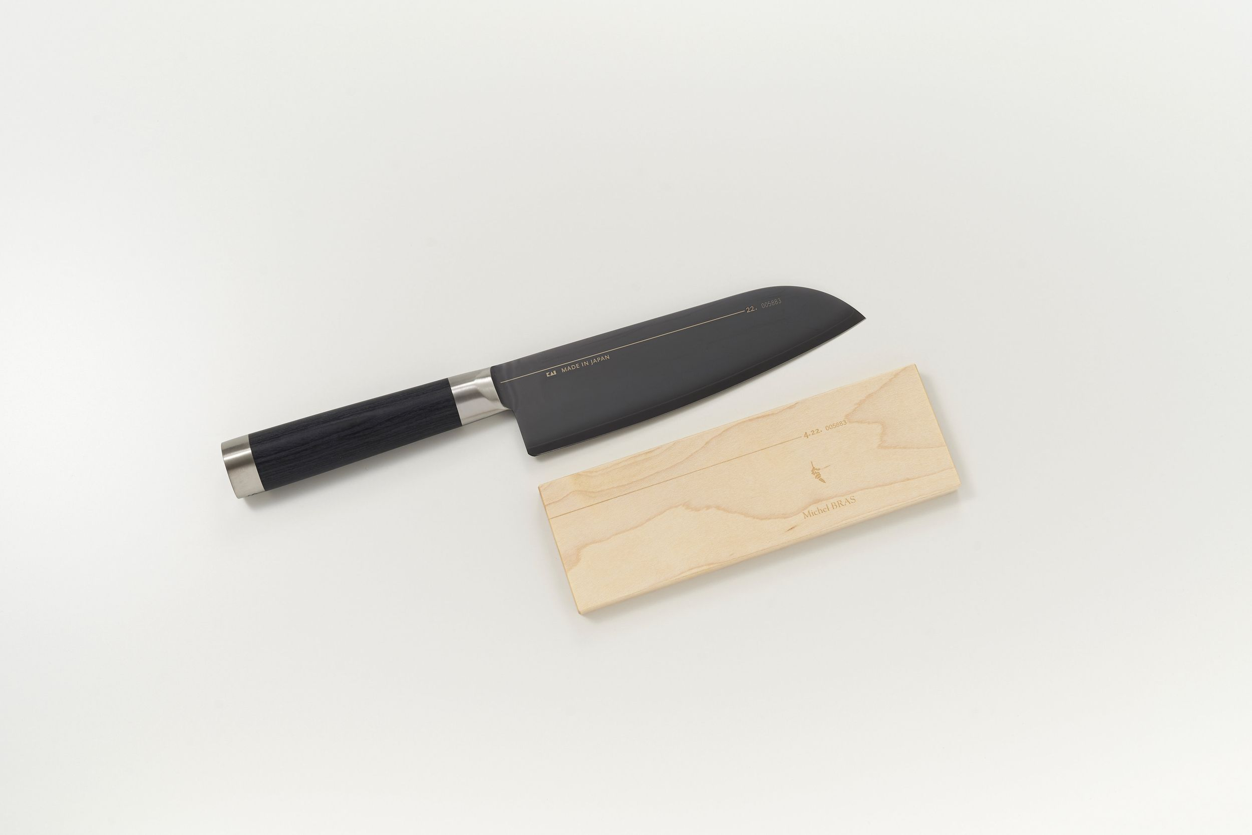 Ein schwarzes Messer mit Holzgriff liegt neben einer Holzbox.