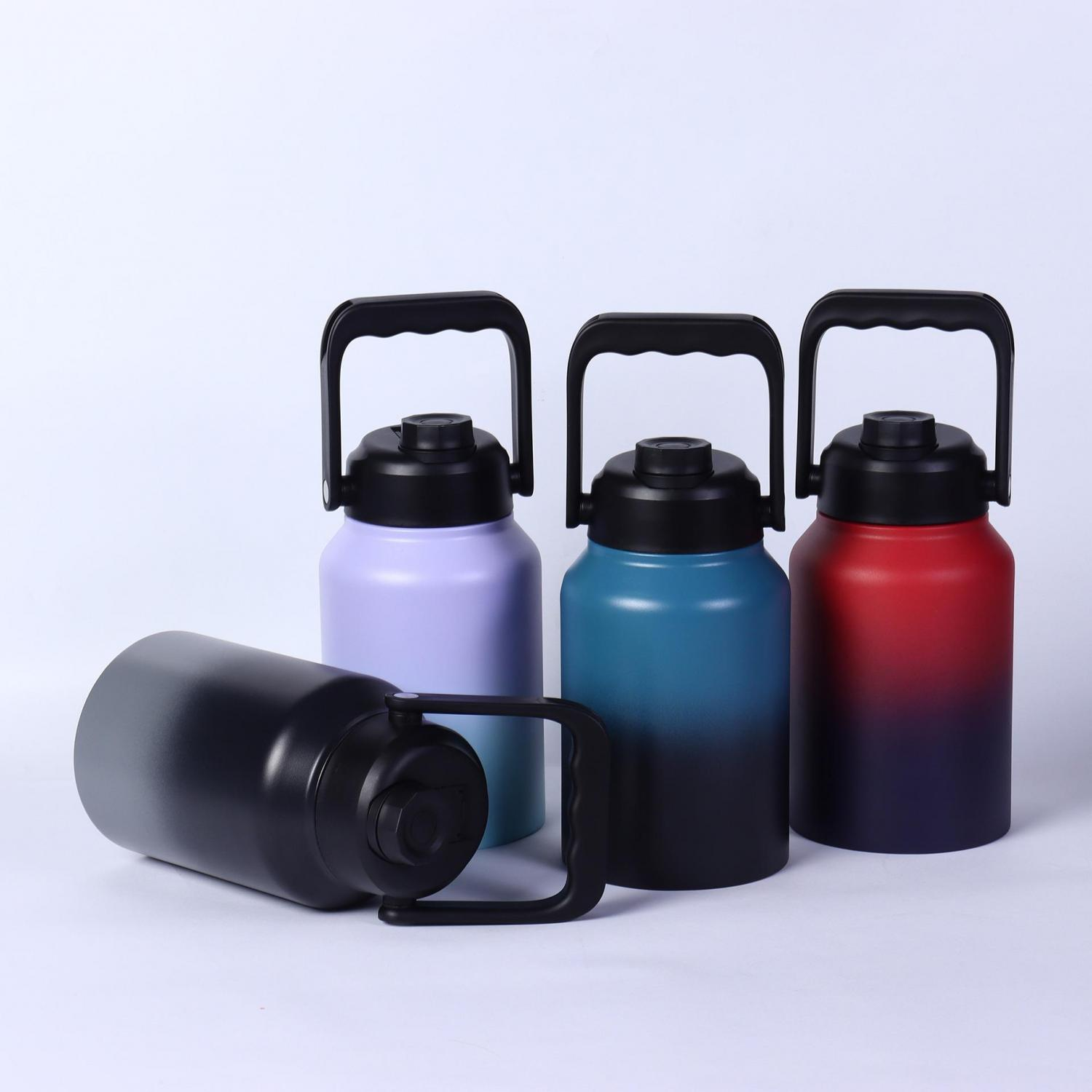 Vier Thermoflaschen mit Griffen: eine schwarze liegend, eine lavendelfarbene, eine blaugrüne und eine rot-violette.