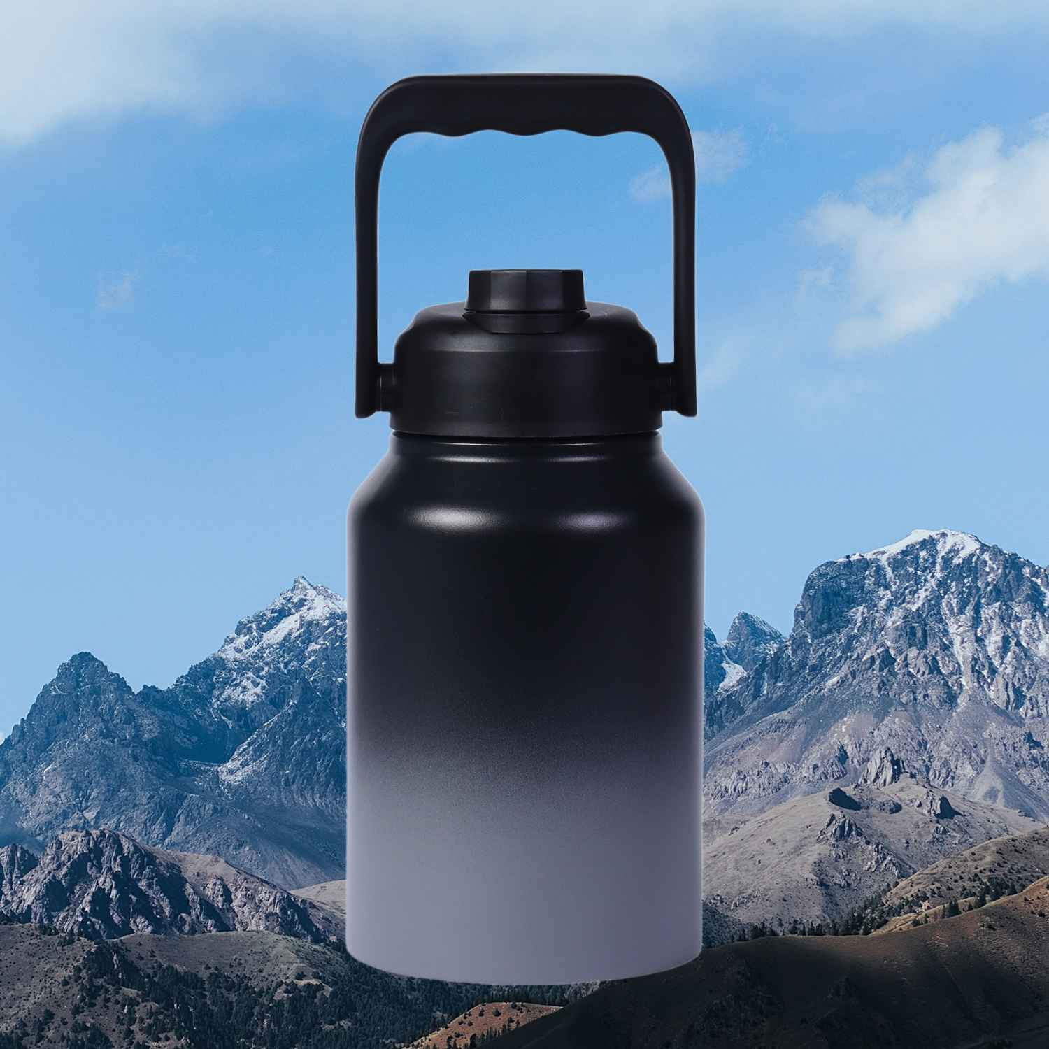 Schwarze Trinkflasche mit Griff vor Bergkulisse und blauem Himmel.