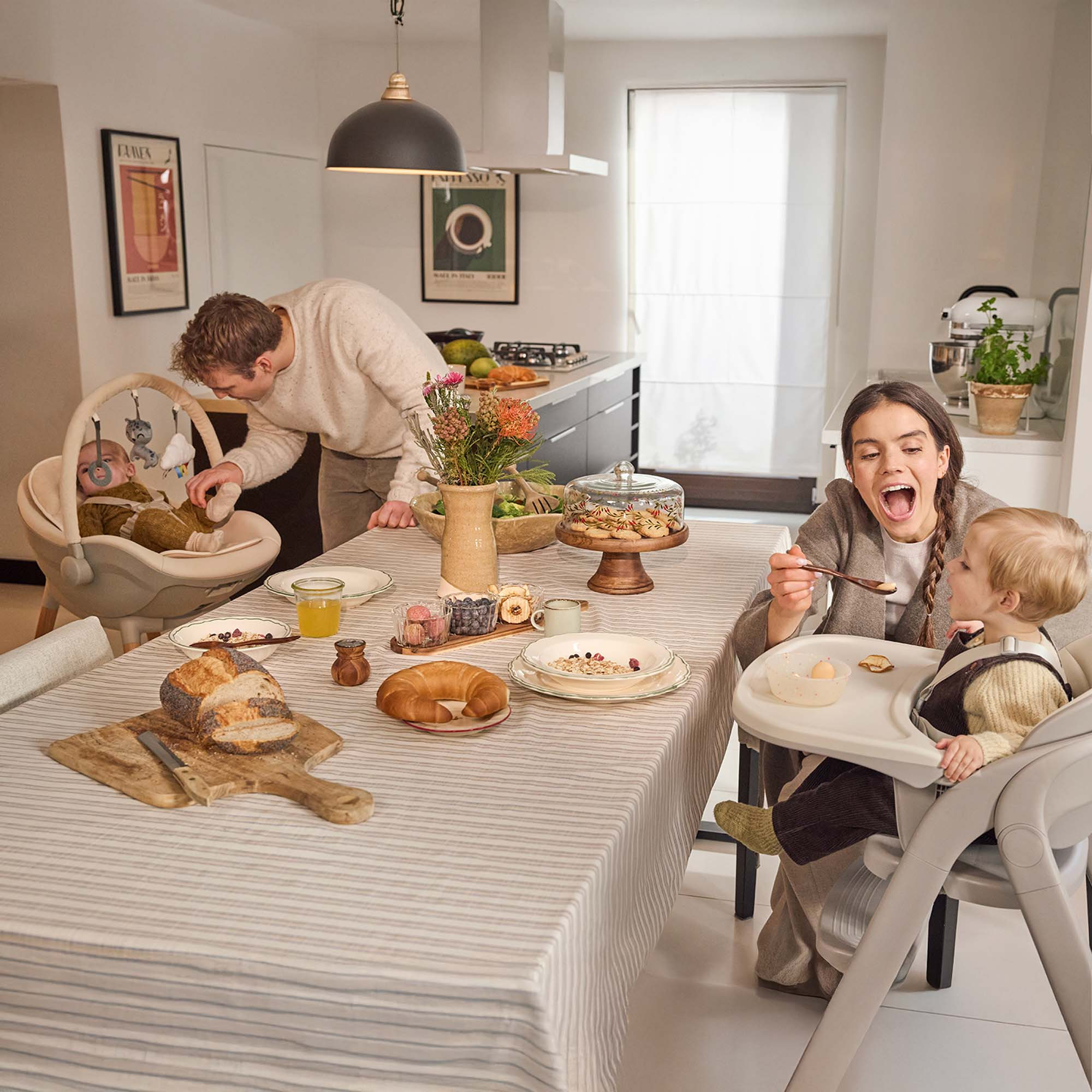 Familie isst in der Küche. Vater mit Baby, Mutter füttert Kind am Tisch.